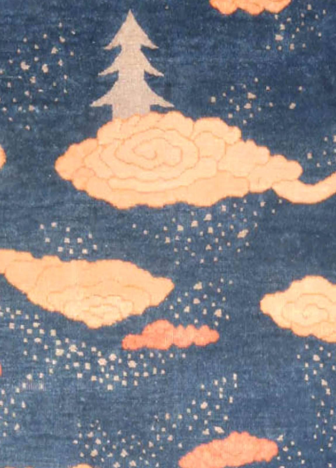A playful example from the DLB collection of Chinese Art Deco rugs, which has a blue field dominated by scattered stylized cloud formations and trees in shades of ivory and orange.