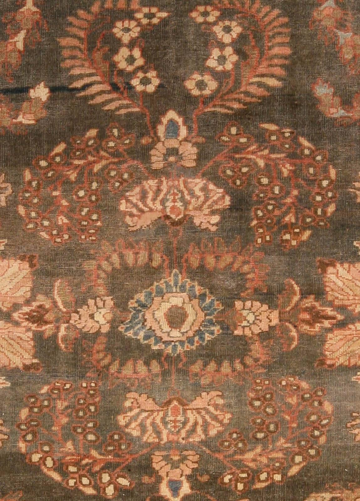 An early 20th century Persian Sultanabad antique carpet, the brown field with a symmetrical pattern of flowing stylized leaves and palmettes in shades of red and beige within a narrow red palmettes border.