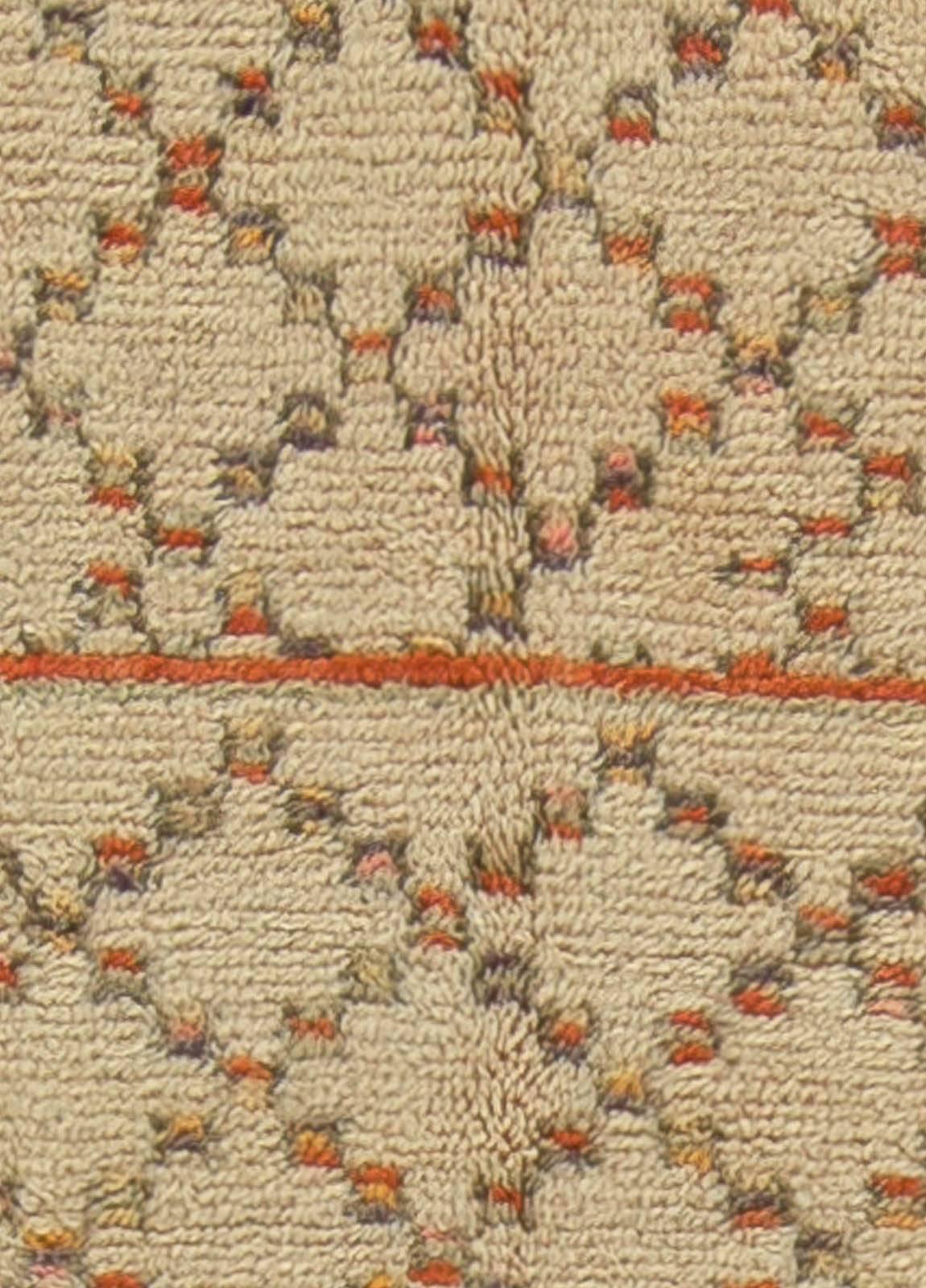 This circa 1940 vintage Moroccan rug features an all-over design of a multicolored lattice in shades of yellow, orange and blue against a field of neutral beige. Stark and Minimalist, the vintage carpet is an intriguing abstract statement.