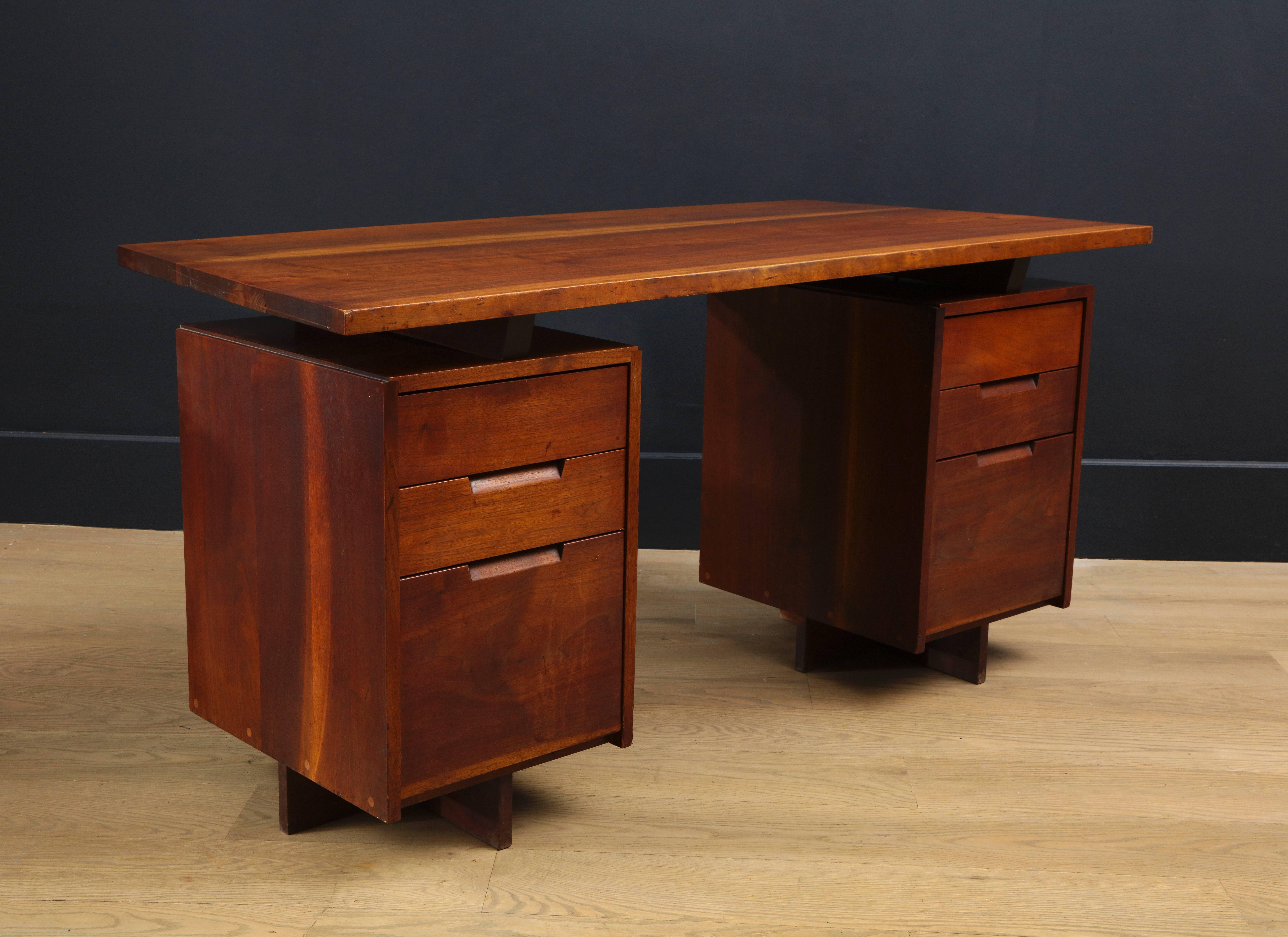 American Studio Movement desk by George Nakashima in black walnut. Double pedestal supports with three drawers with a curving and tapered top. With one previous owner who acquired this desk directly from Nakashima.