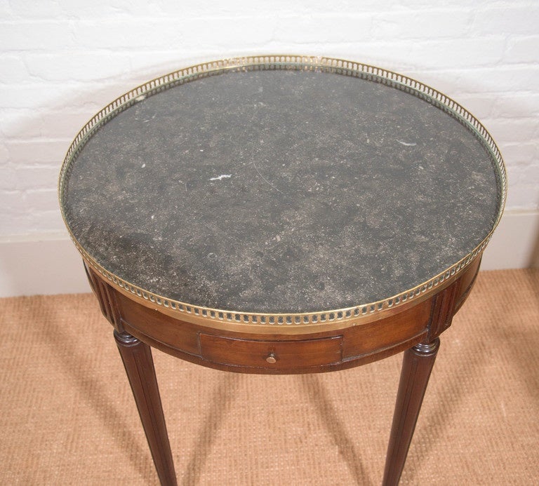 Round Louis XVI marble-top Bouillote game table with two drawers and two candle pulls and brass gallery