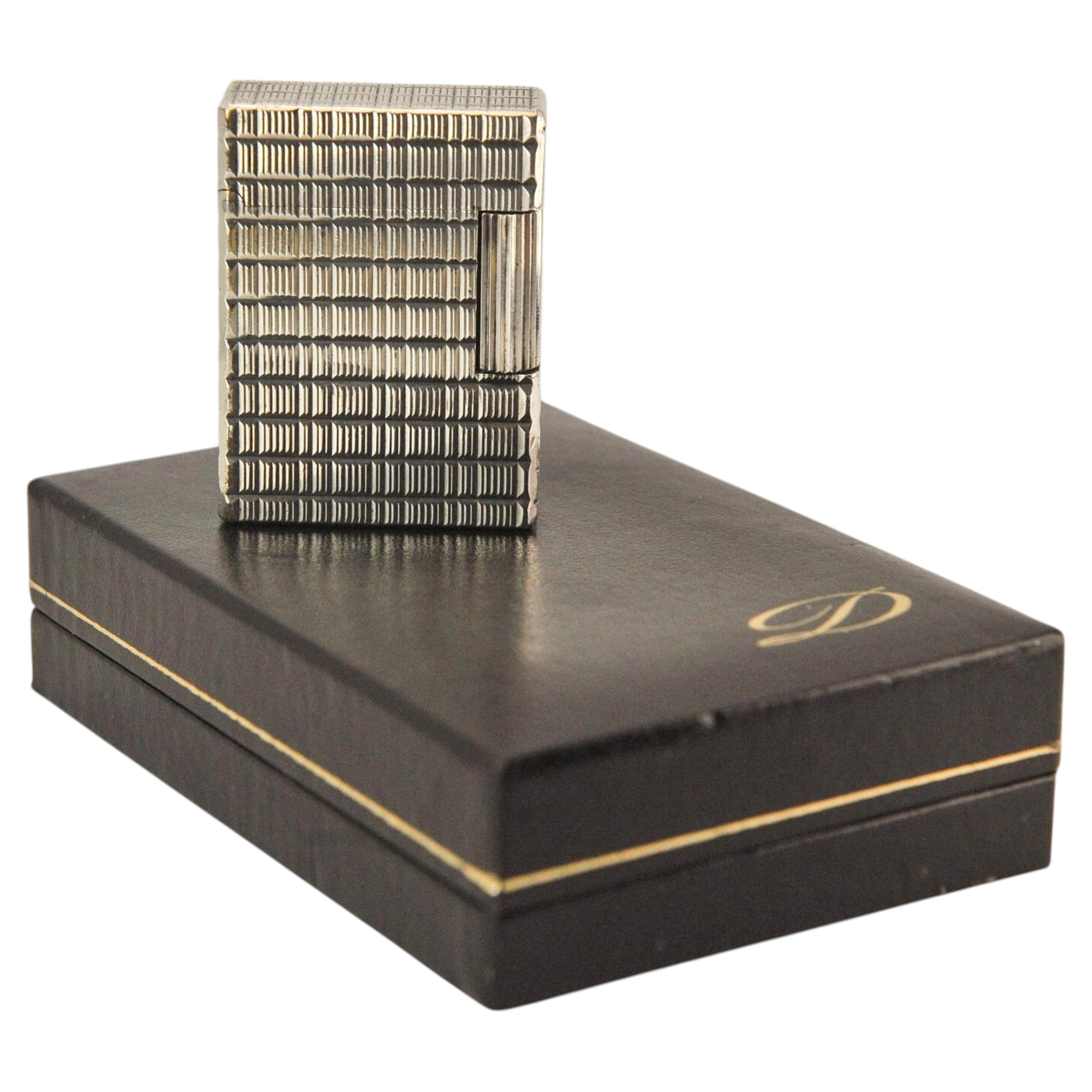Un petit briquet à cigarettes Dupont en métal argenté de la gamme Ligne 1, dans son coffret et révisé