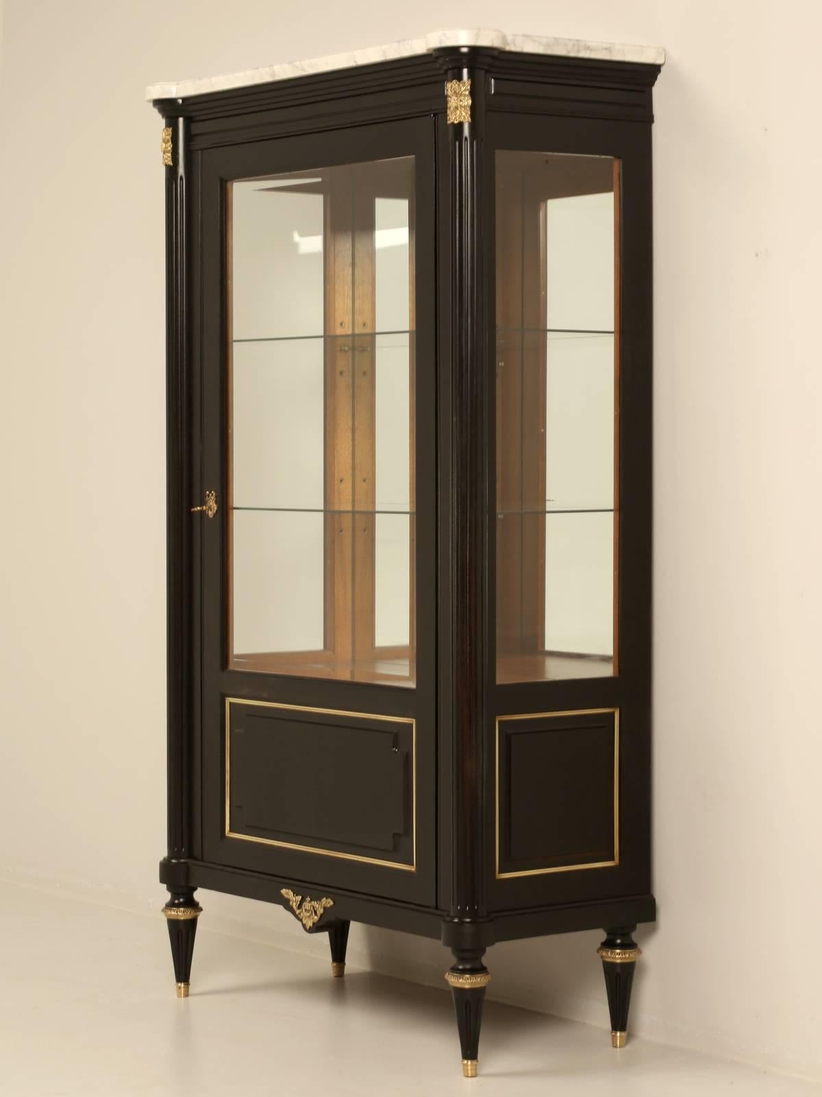 French Louis XVI vitrine, china, or curio cabinet made in France from mahogany during the mid-1900s. Our workshop carefully hand stripped the exterior and applied a very nice old fashion ebonized finish, where all of the mahogany grain still shows