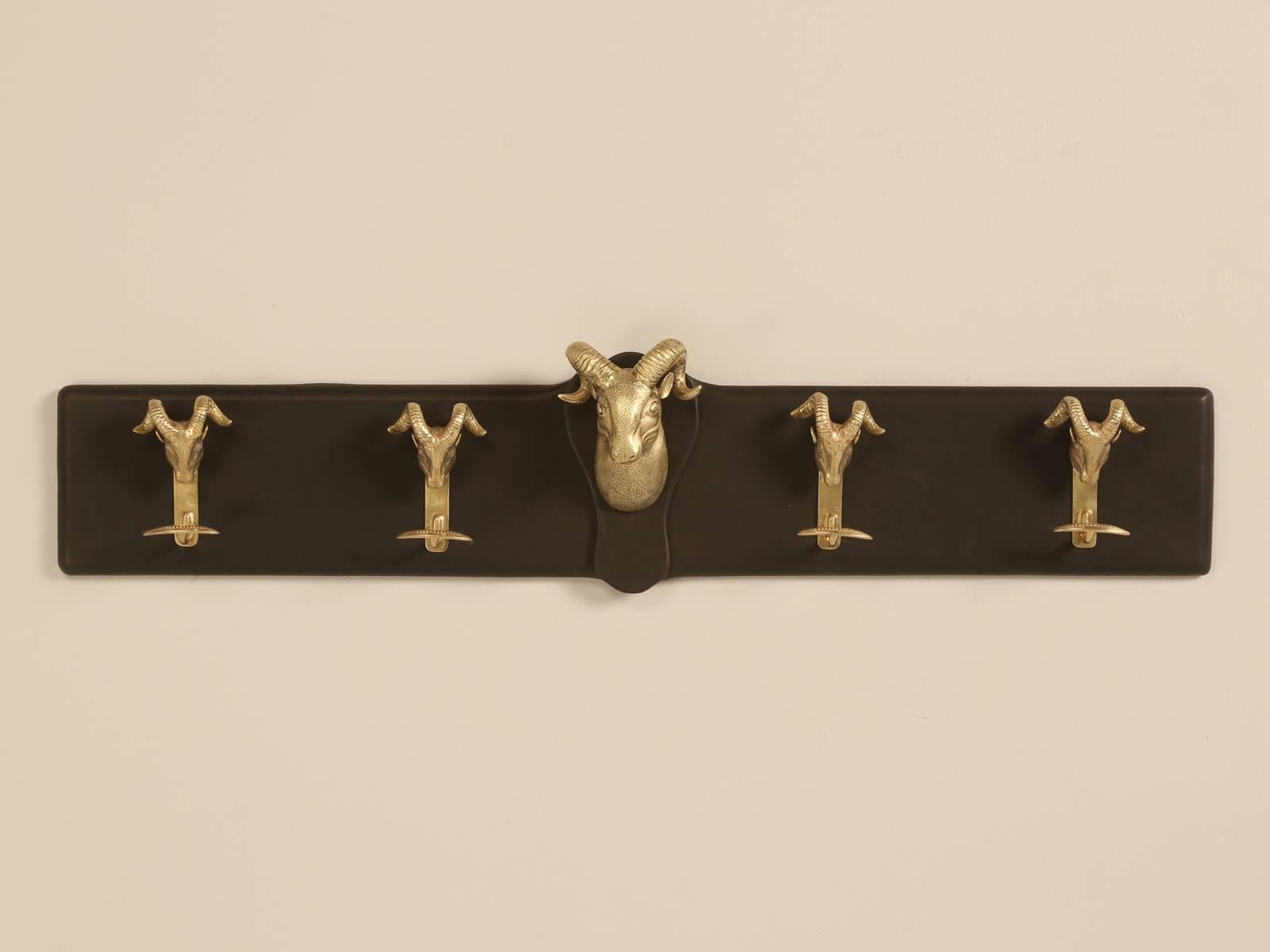 Vintage French solid brass Ram’s head coat rack, mounted on a black leather covered wood frame.
