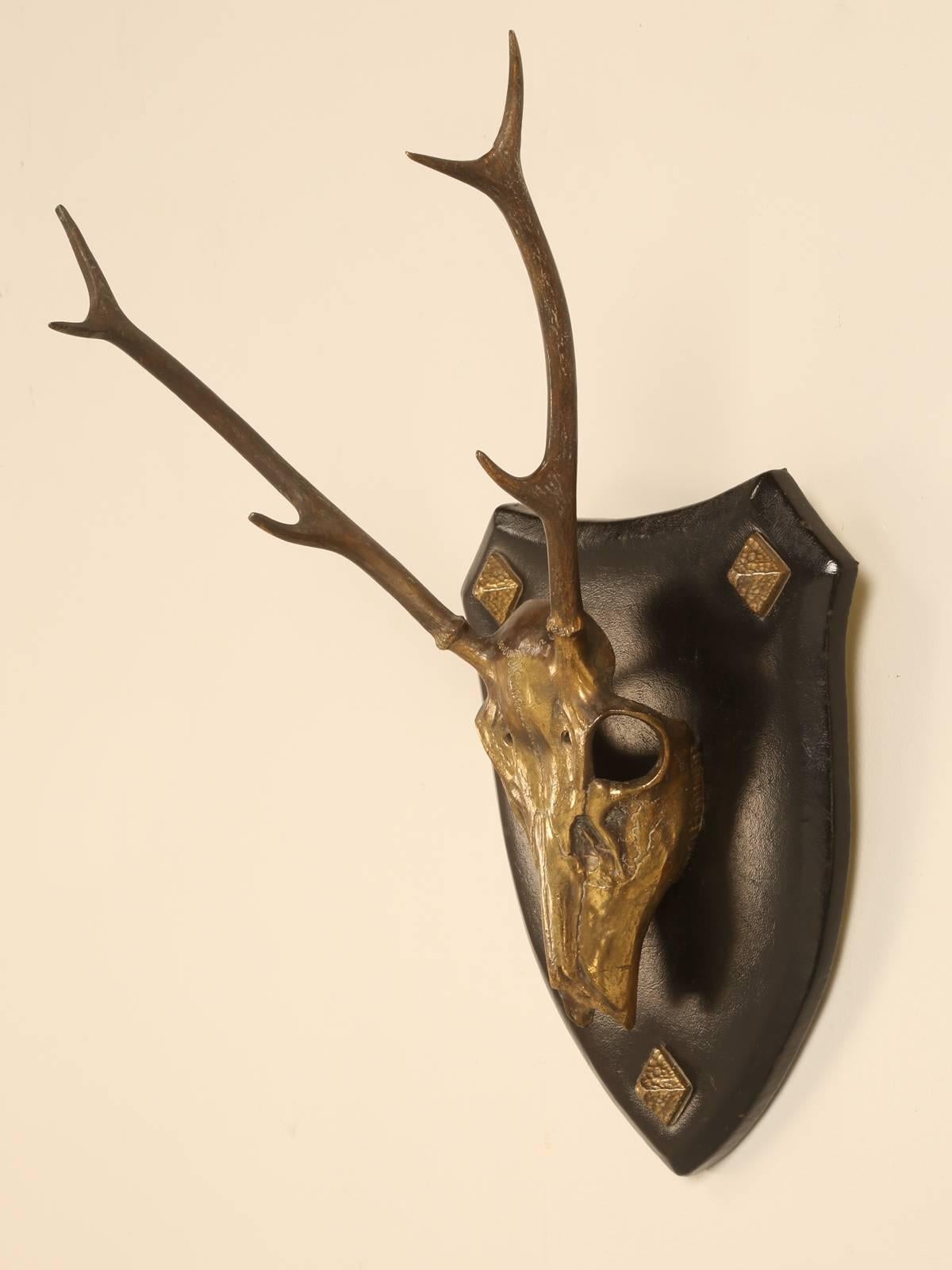 Artfully sculpted stag head was made in France probably during the 1950s and was cast from solid brass and then hand-polished before mounting on a leather covered mount. The antlers had a patina applied in order to darken and have a contrast with