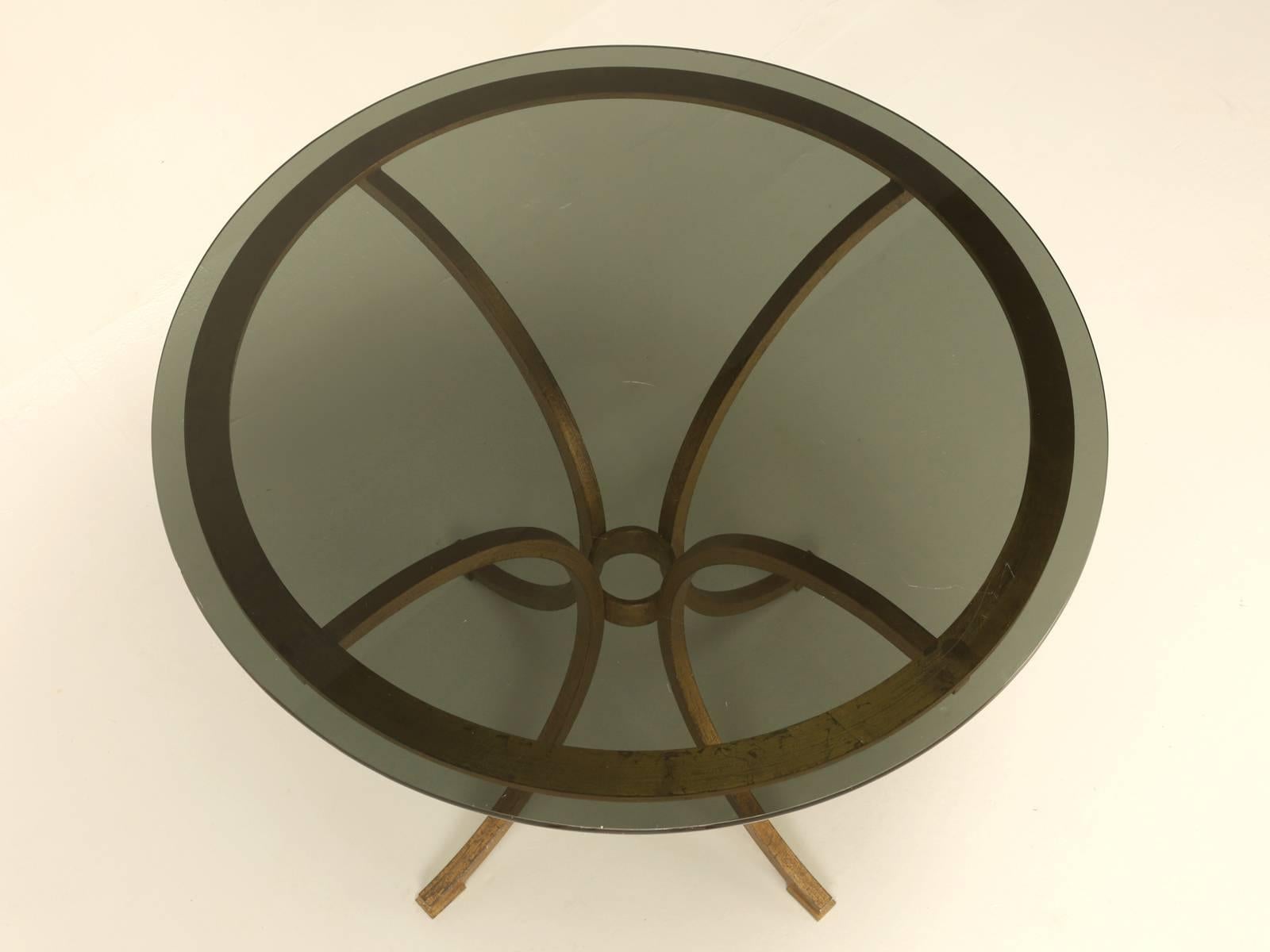 French mid-century modern, gilded forged iron table which can be used in a multitude of locations. Such as an end table next to a sofa, a center hall table in your entry foyer, to a small kitchen table. The smoky glass top is not original to the