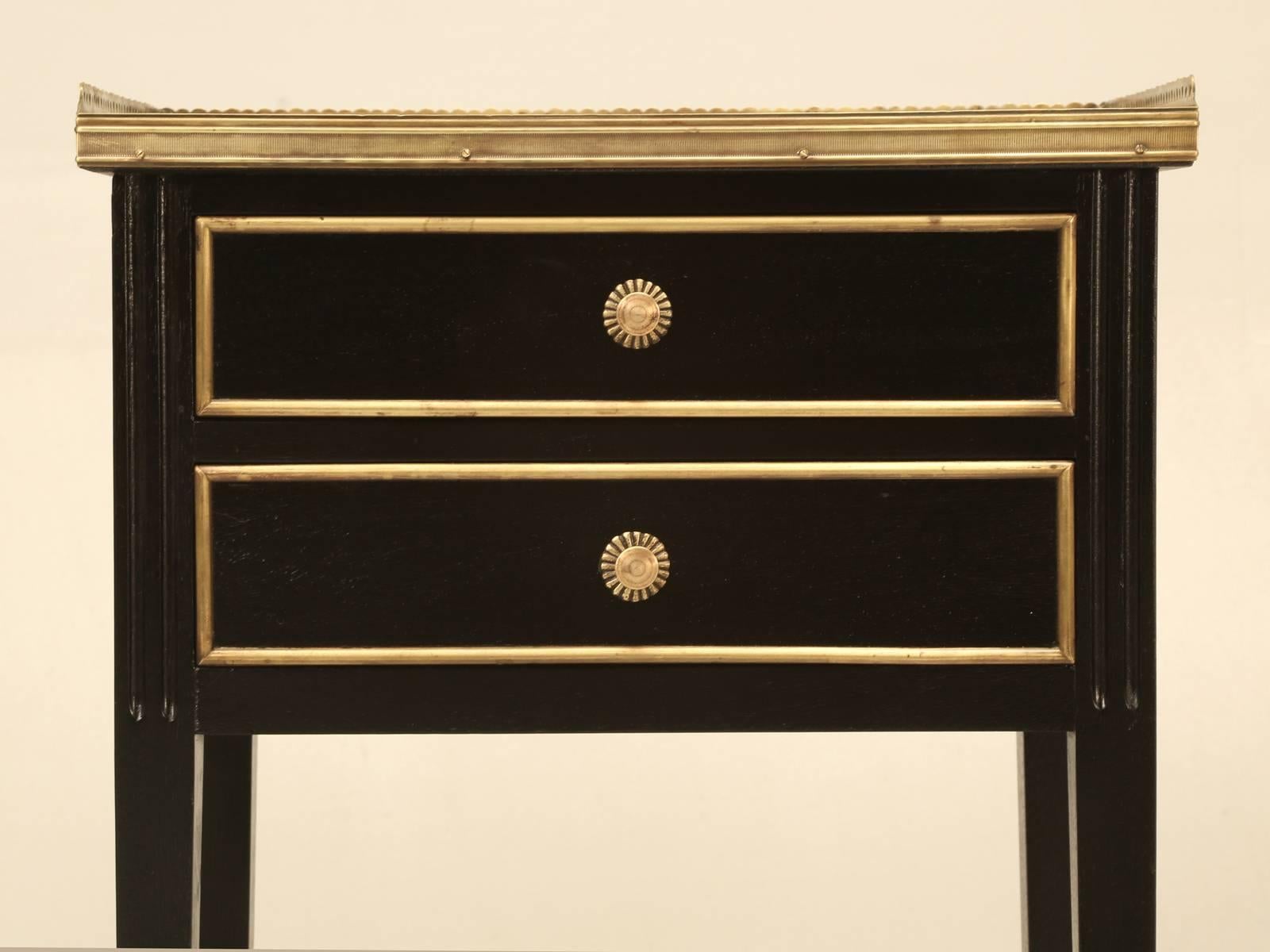 Vintage French matched pair of Louis XVI nightstands, with Carrera marble and a brass gallery detail. Our Old Plank workshop hand-stripped the mahogany and applied an old style ebonized finish and slightly cleaned the brass detail moldings. 
Height