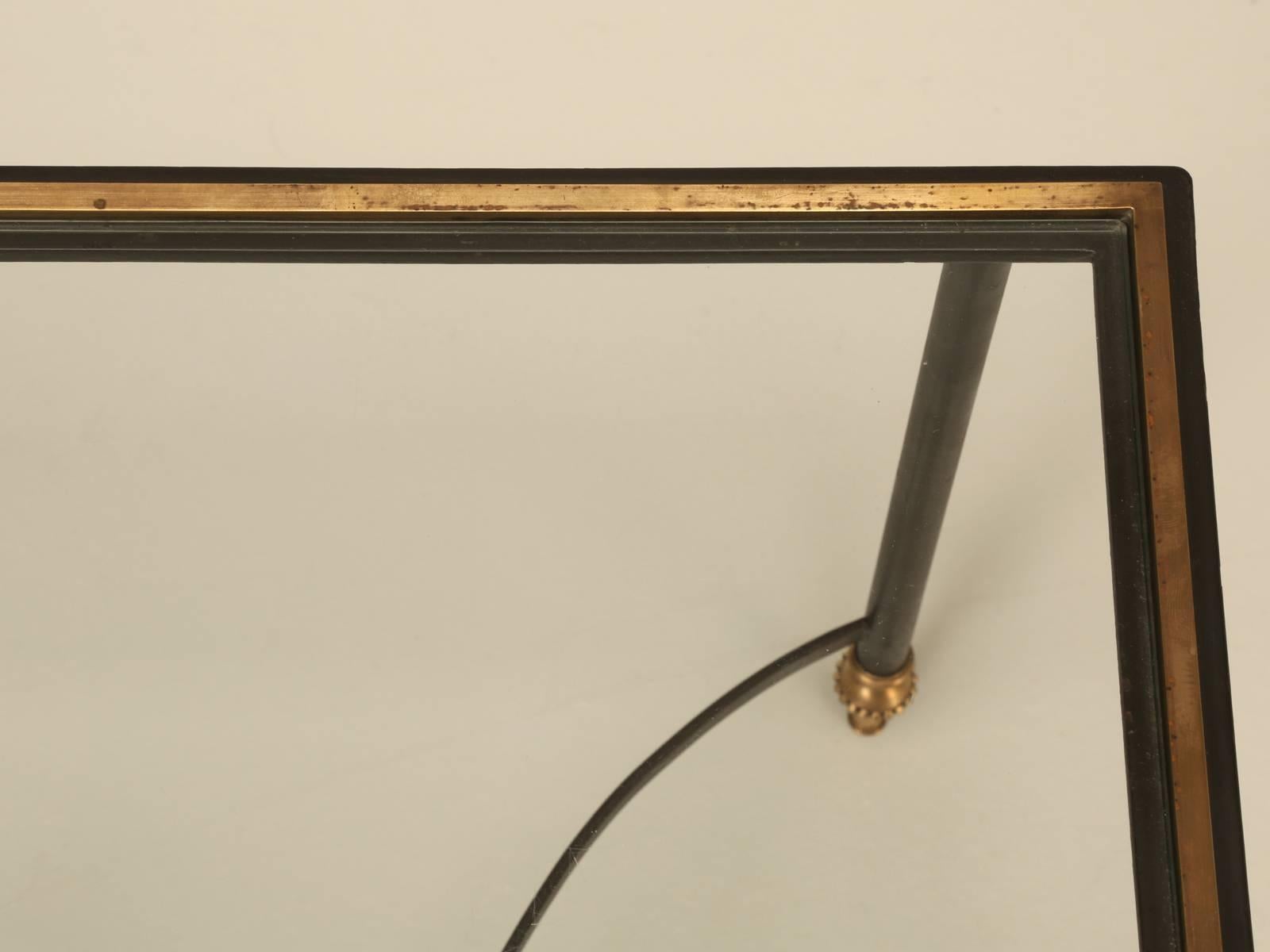 French Mid-Century Modern coffee table done in a mix of solid brass and steel, which is a bit unusual and rather elegant. The glass is original to the table and is of course a bit scratched up and we will be happy to replace it, but some of you