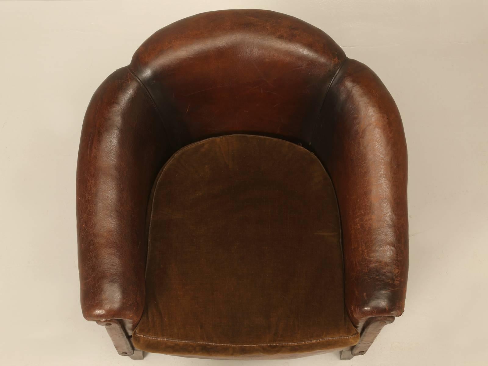 French barrelback leather chair in an all original condition and I believe even the old worn velvet on the down filled seat cushion is correct, just like you would expect on a French leather club chair. For the last 25-year’s, we have been enamored