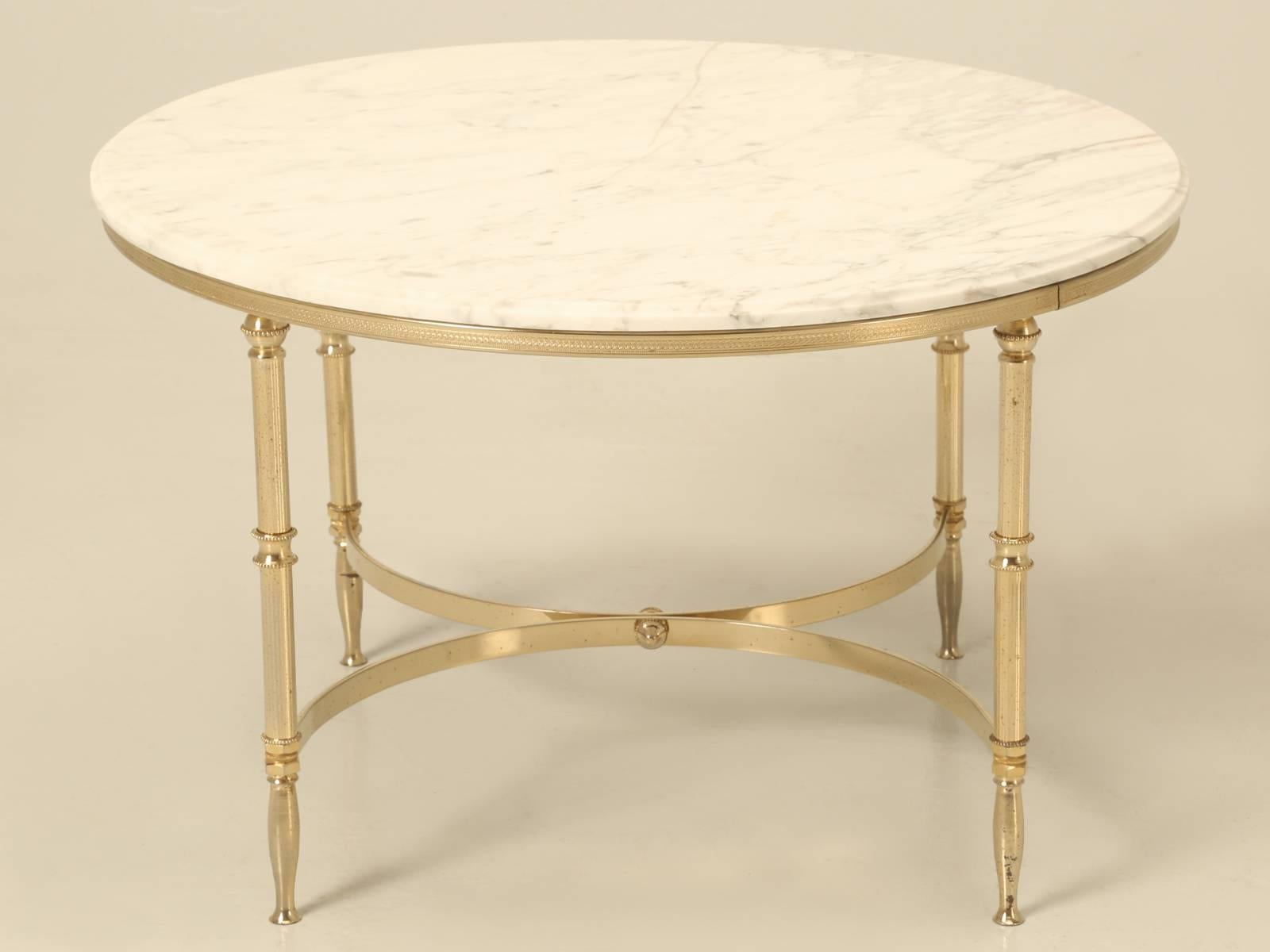 Vintage French, Mid-Century Modern round marble and brass coffee table. Although the marble looks like it was broke and repaired, it actually was not, for it is just a hairline in the marble itself.