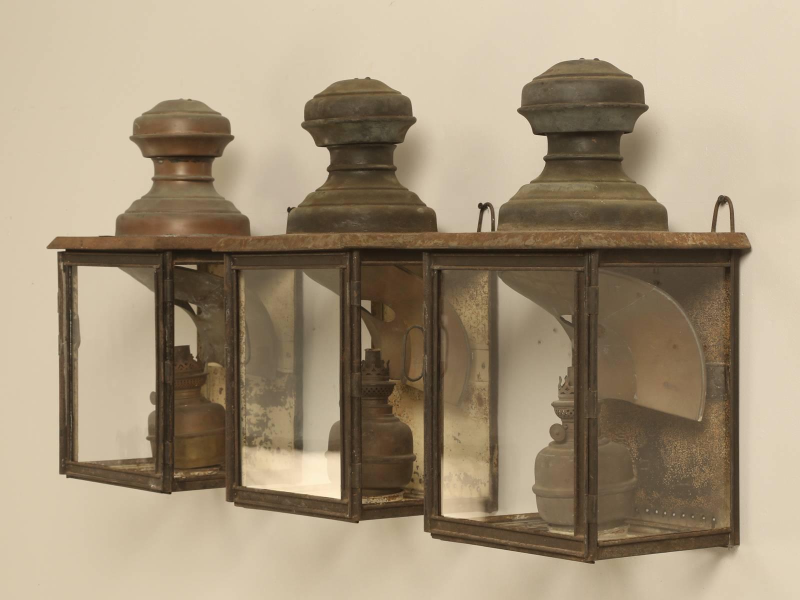 Wonderful set of three Antique French Lanterns from the 1800s with their old handmade French wavy glass and the kerosene canisters still in place. The patina is exactly how they were found and other than cleaning the glass, the lanterns are