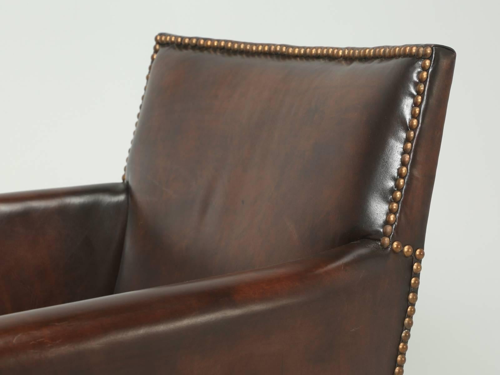 French leather club chairs that our, in house Old Plank upholstery department have completely disassembled and rebuilt from the wooden frame on up. Much of the leather on the club chairs is original and what is not, we hand dyed to match the