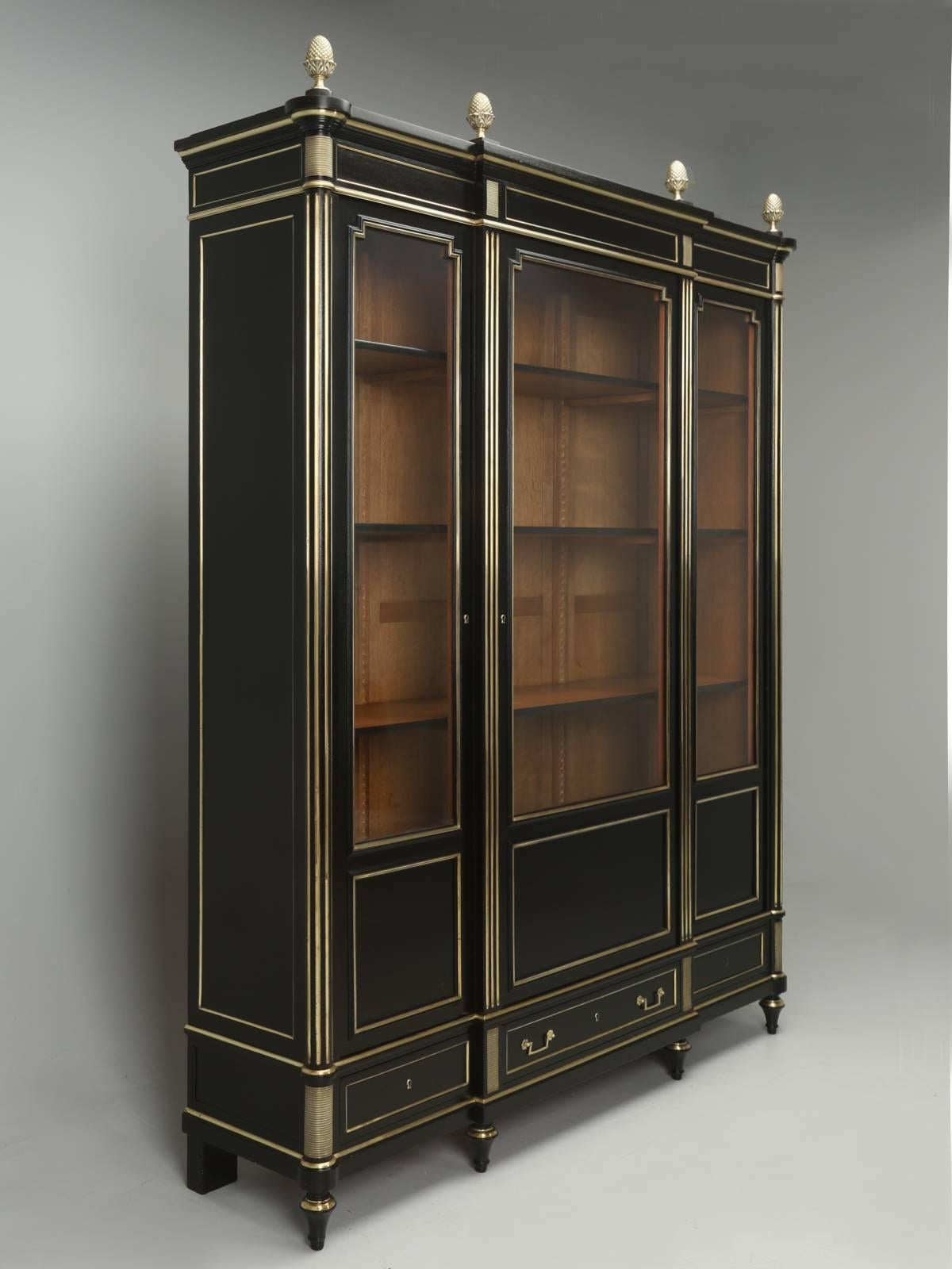 Antique French ebonized bookcase, made from solid mahogany with brass trim, circa 1900. The interior features fully adjustable shelves made from French white oak. Exterior has three drawers under the glass doors. This antique French ebonized