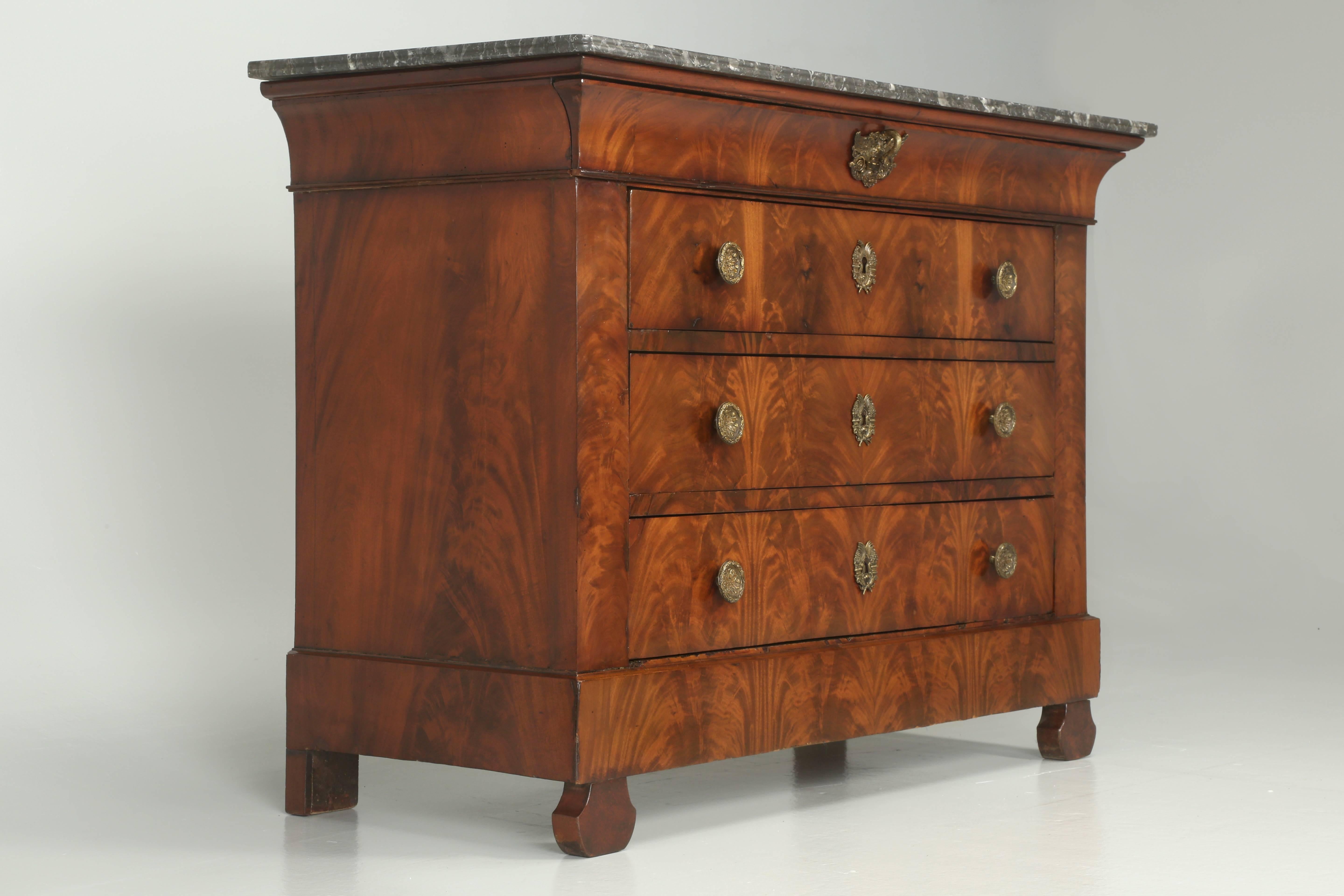 Antique French Commode or chest of drawers, done in a crotch mahogany book-matched veneer that was just gone through by our Old Plank finishing department. The rich color of the mahogany plays beautifully with the contrasting hardware. The upper