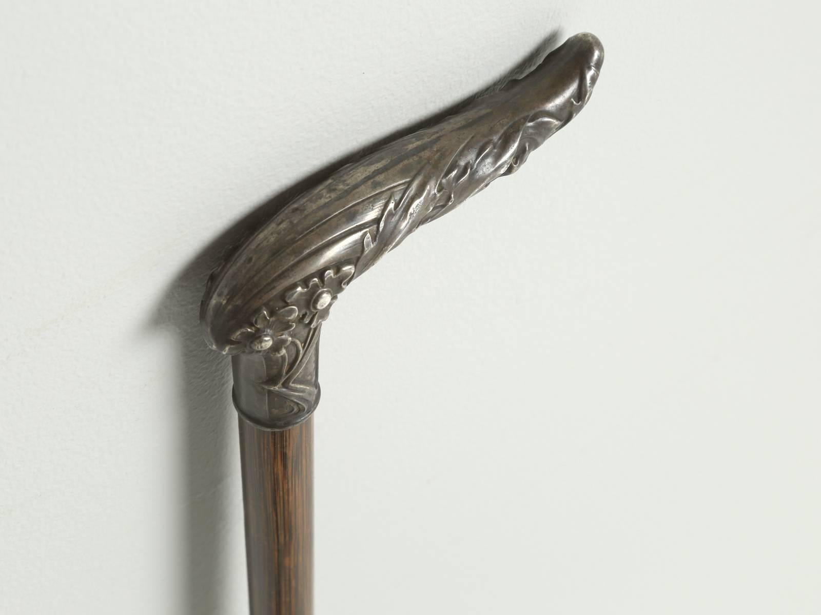 This particular walking stick appears to have been made for a woman, for it is lighter and more delicate in execution. There is even a hint of Art Nouveau in the flowers on the embossed silver handle. The shaft is done in a Fine striated finish