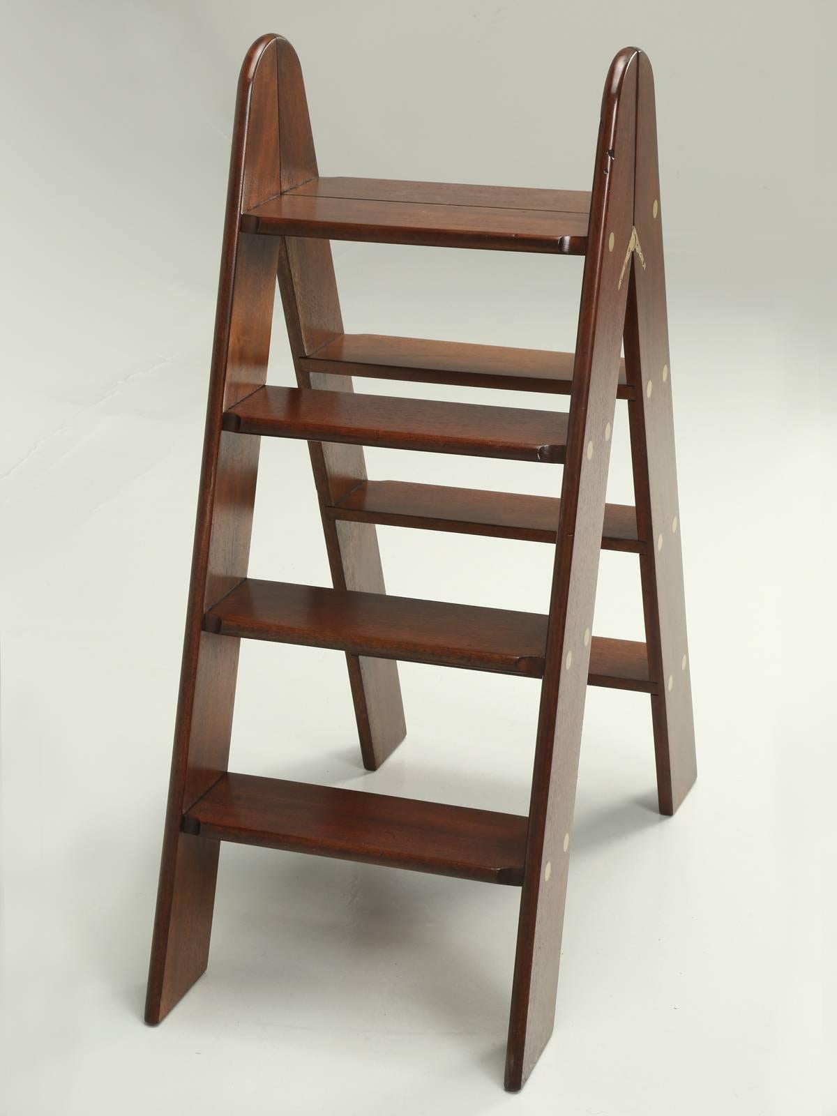 Beautifully constructed from solid mahogany and brass and would look great with some old leather- bound books sitting on the ladder. Kind of difficult to date, but our old plank finishing department, did have to refinish the mahogany ladder and