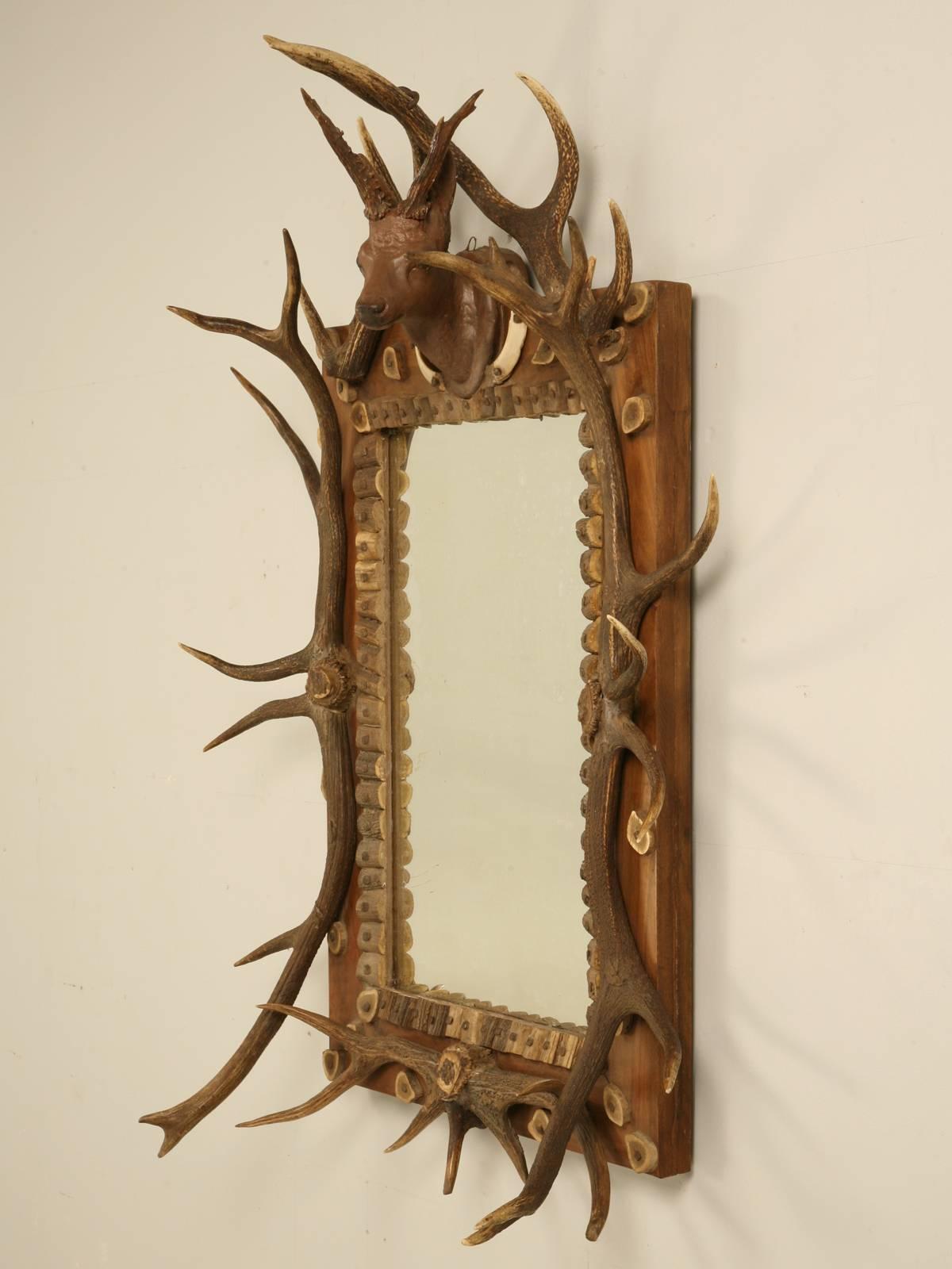Antique Black Forest mirror with exceptional attention to detail from the European Red deer antlers on the perimeter, to the Eastern Roe Deer antlers for the center mount. The Russian Boar tusks flank the hand carved wooden deer head at the top