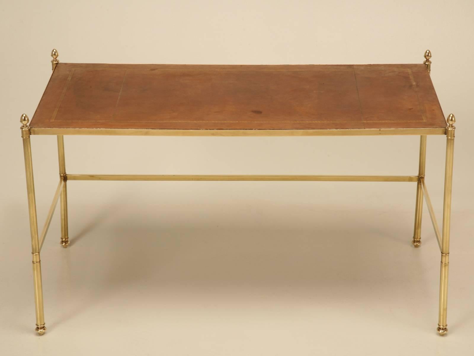 Elegant French mid-century modern coffee table made from brass and adorned with a leather top. Probably made in the 1960’s and is a refreshing change from all the mirrored top tables they produced in that era. 
**Height provided does not include