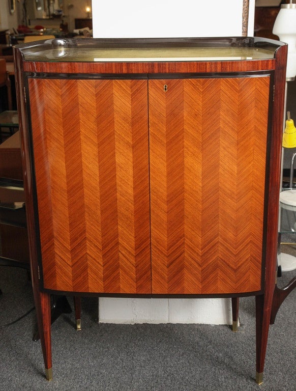 Stunning liquor cabinet made in Milan, 1950 designed by Paolo Buffa. Double doors done in parquetry rosewood sides and legs in darker rosewood, interior in mirror and glass, top in reverse gold leaf, great quality.