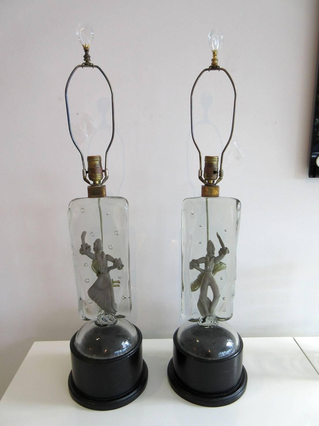 A rare pair of Murano glass lamps by Barbini. The thick slab body of the lamps have silver tone dancers-- male and female. The bases of these lamps are original and the glass finials are included. The lamps are working.
  