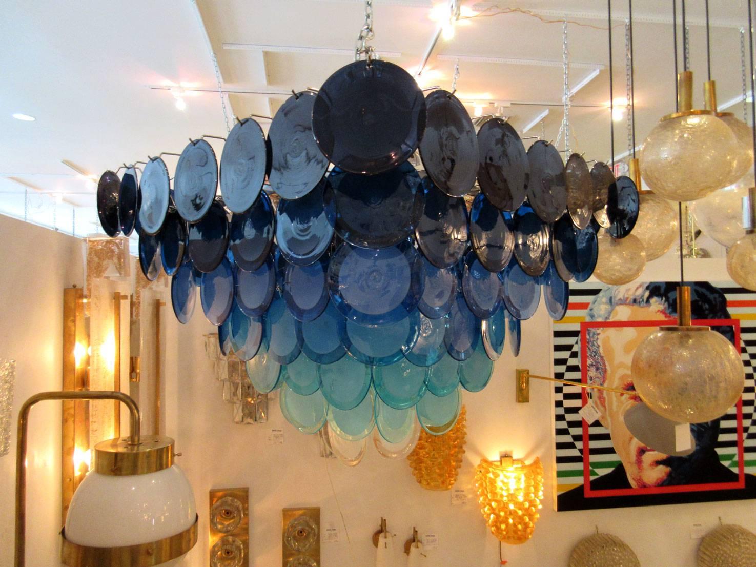 Gorgeous seven-tiered Murano glass disc chandelier by Vistosi. The 100 individual glass discs are arranged in an inverted pyramid shape, and the colors form an ombre gradient from dark navy to a rich royal blue to light blue to white. The armature