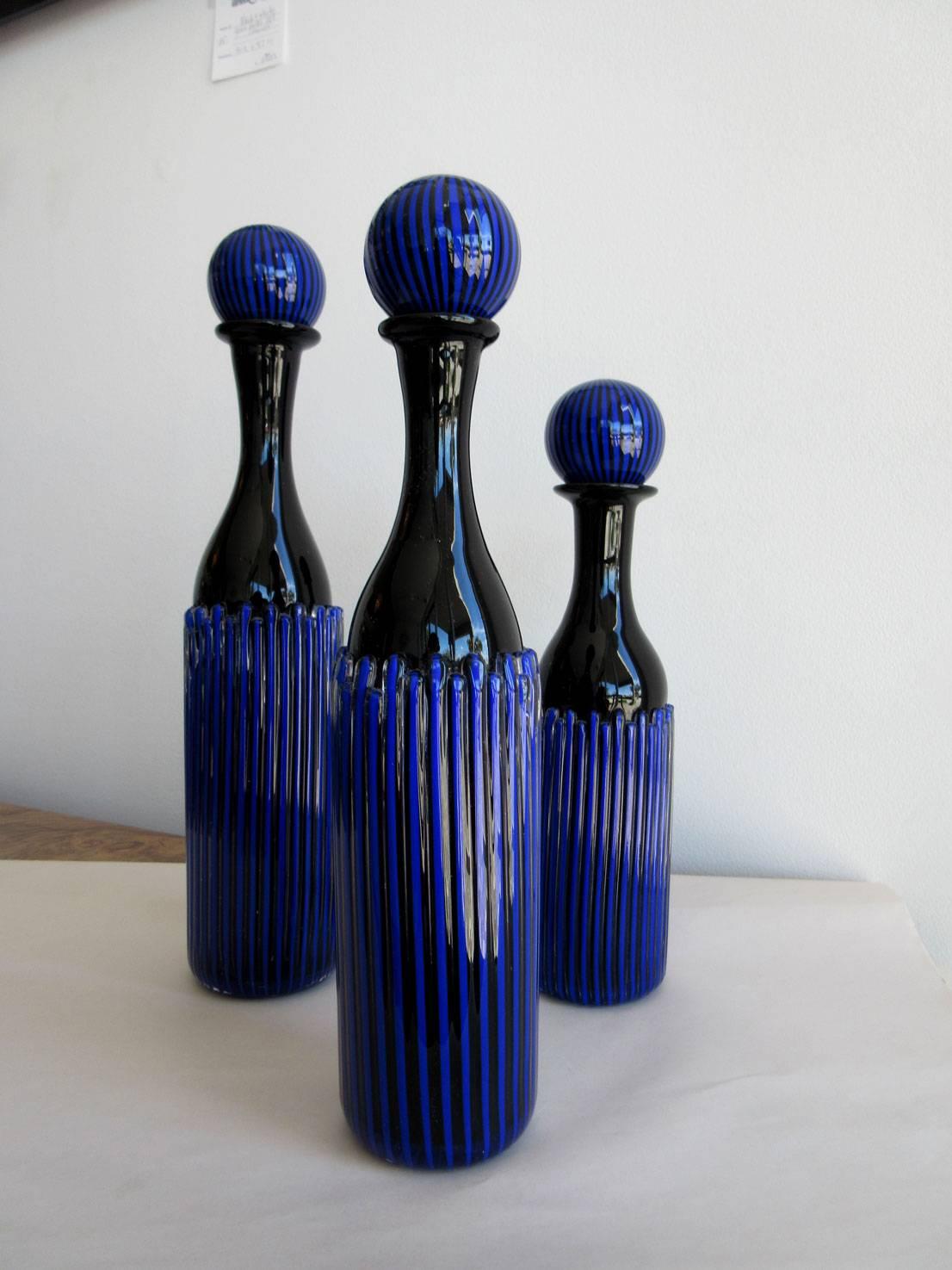 Set of three black and blue decanters with applied canes around the bodies of each piece. The decanters are all signed, Peter Greenwood, 1988.


             