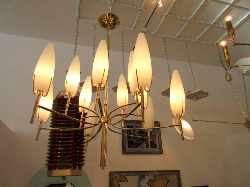 Vintage brass chandelier with twelve arms and candelabra sockets and conical frosted glass shades.