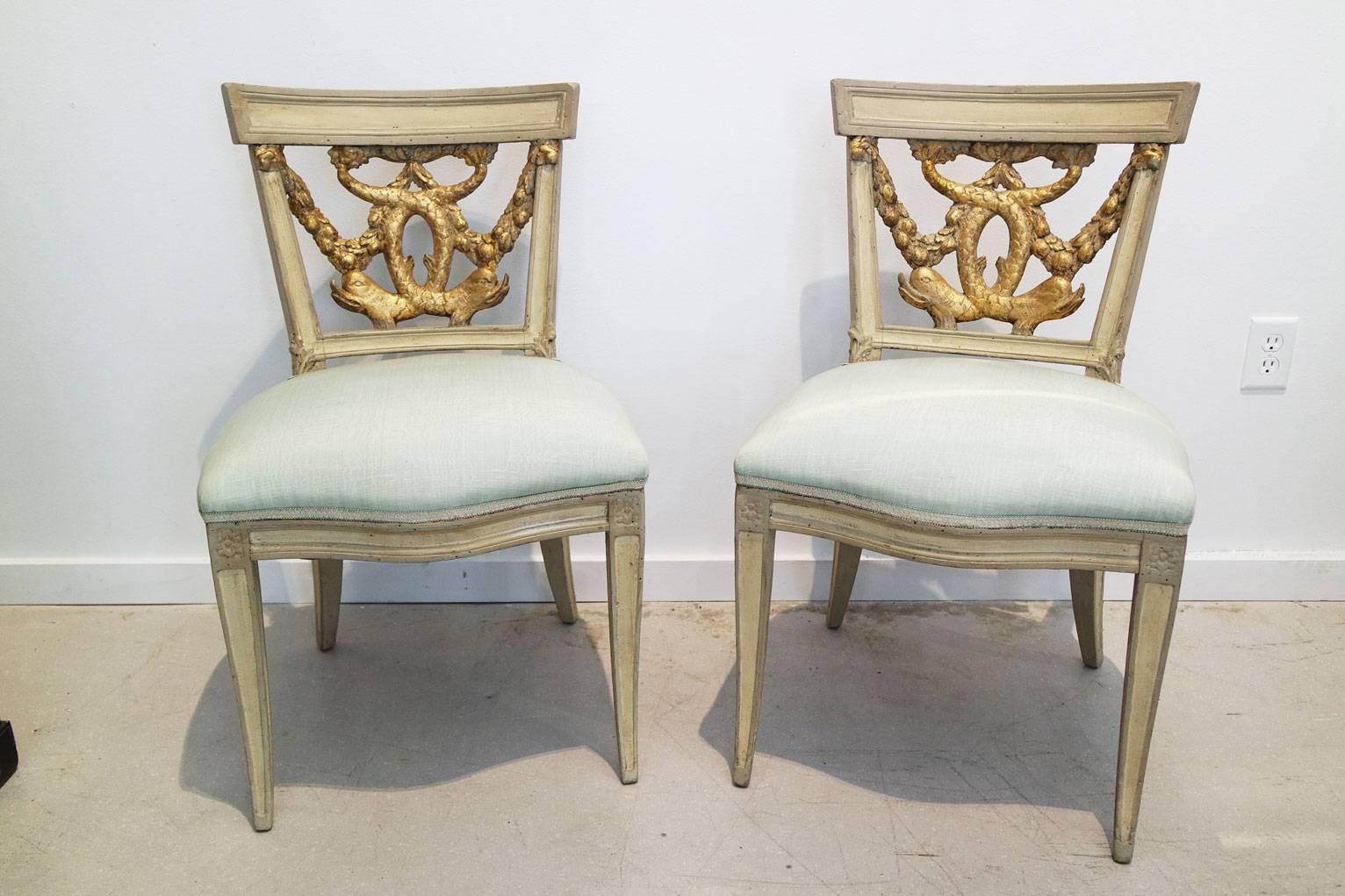 A pair of Italian neoclassical painted and partial gilt side chairs. Last quarter 18th century with dolphin and foliate swags.