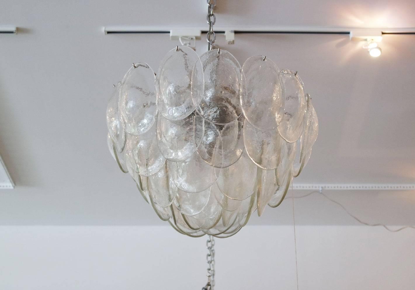 Large five-tiered Vistosi chandelier with turtle-back glass pieces. The armature is chrome and there are six candelabra sockets.