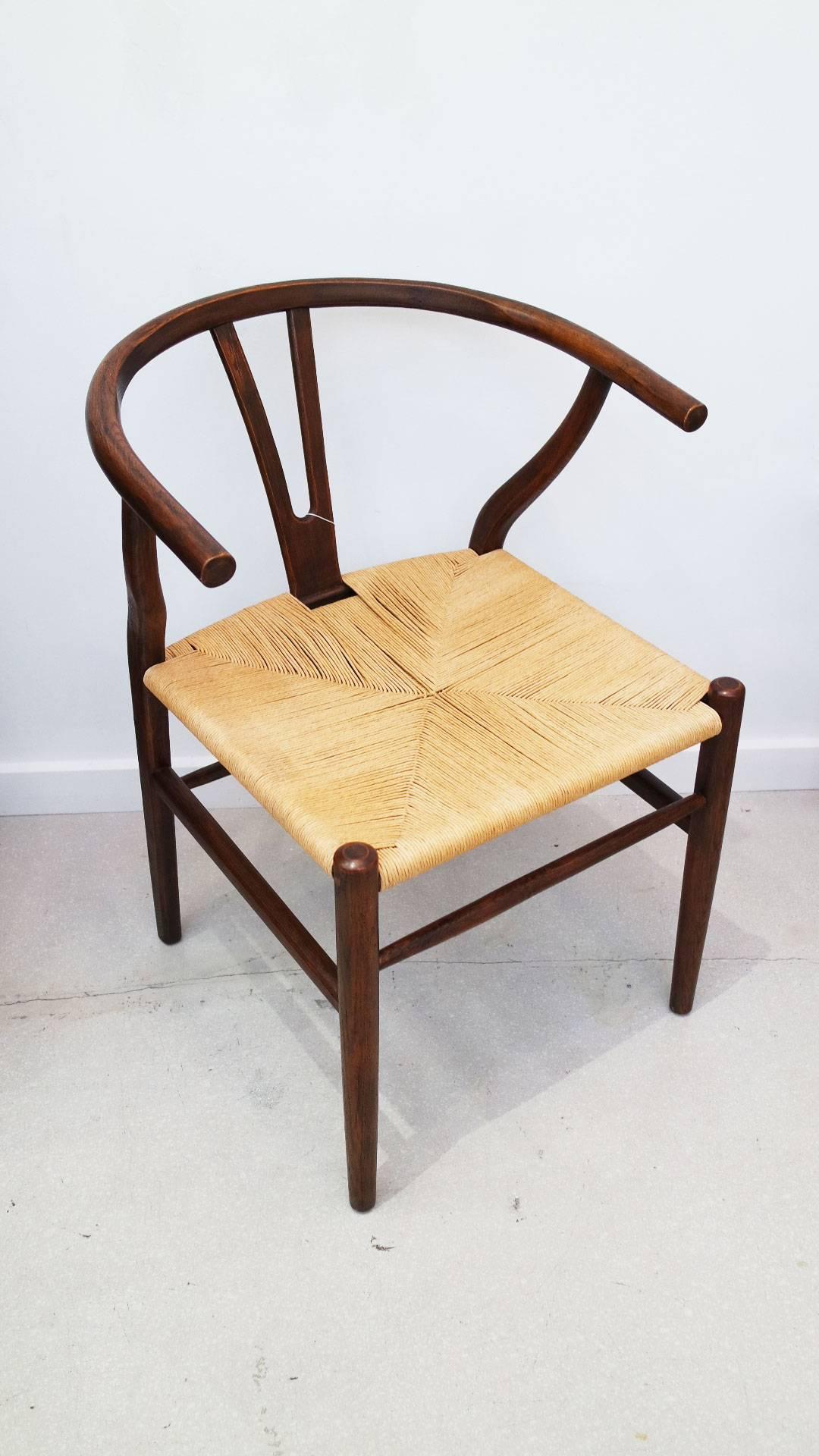 Single iconic Mid-Century Modern wishbone chair by Hans Wegner for Carl Hansen in tobacco stained oak with handwoven paper cord seat.