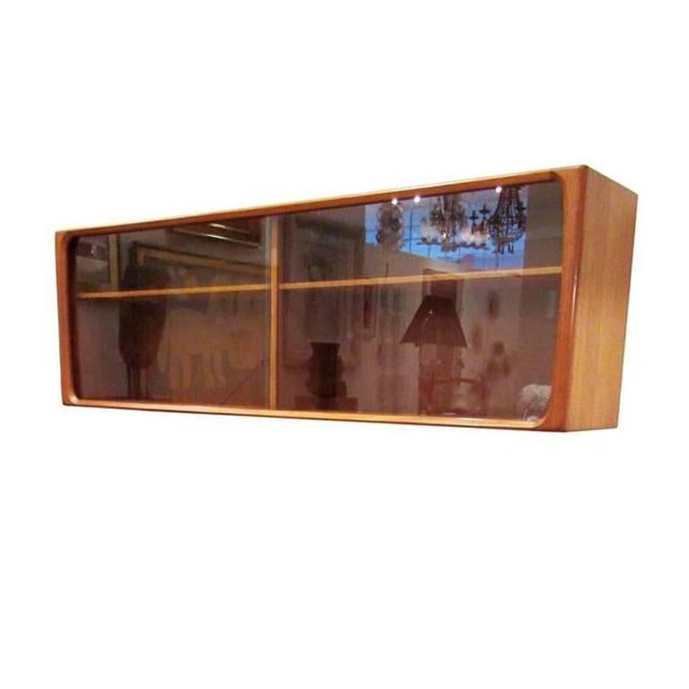 Danish modern teakwood floating cabinet both made by Bernhard Pedersen & Son. The floating cabinet has glass doors as well as original 10 inch supports that can be attached at the base, if one wanted to make it in to another credenza. Each piece