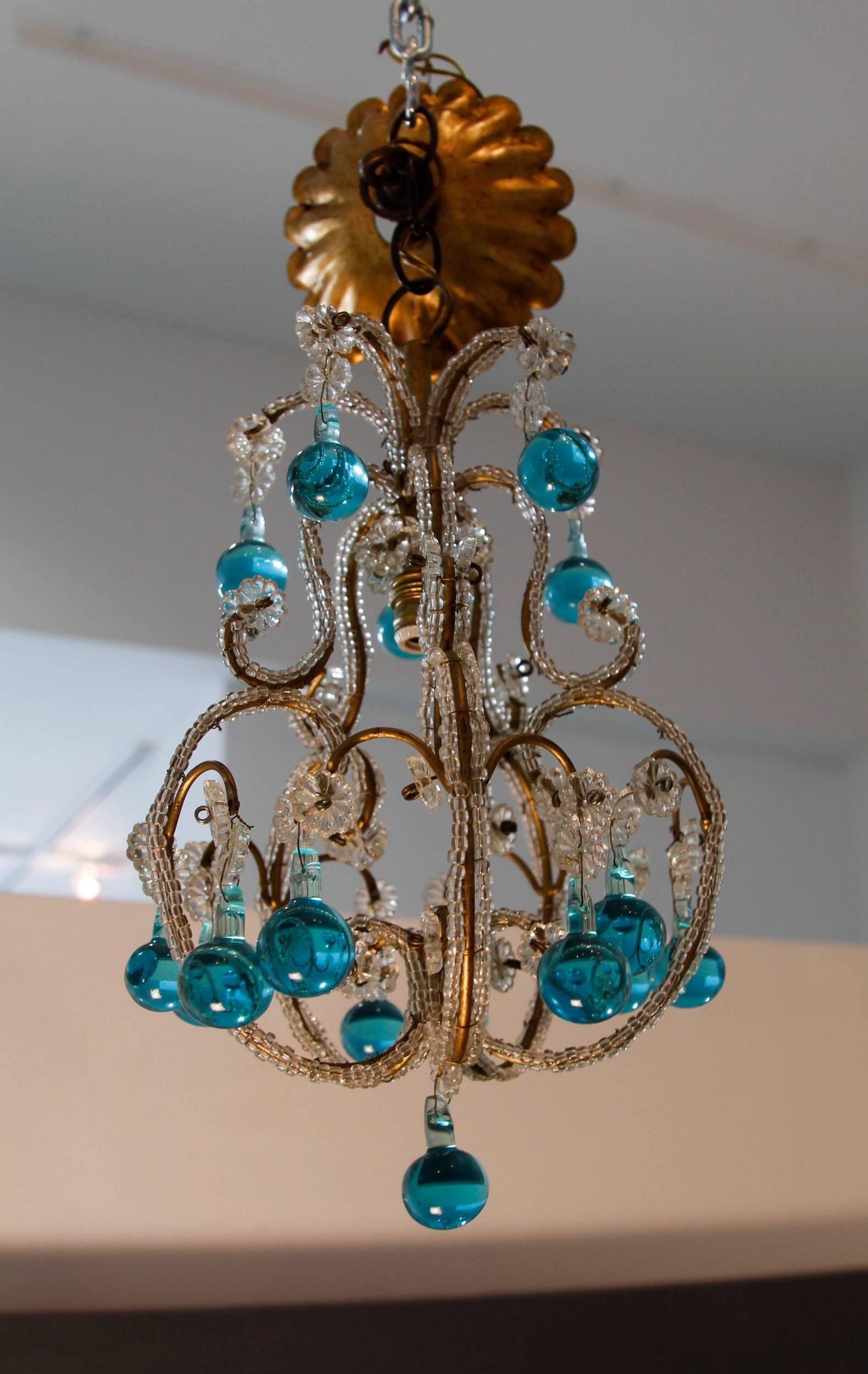 Pair of vintage turquoise blue Murano glass beaded chandeliers with tiny clear glass beads wrapping the cage armatures. We also have the co-ordinating sconces in the gallery.