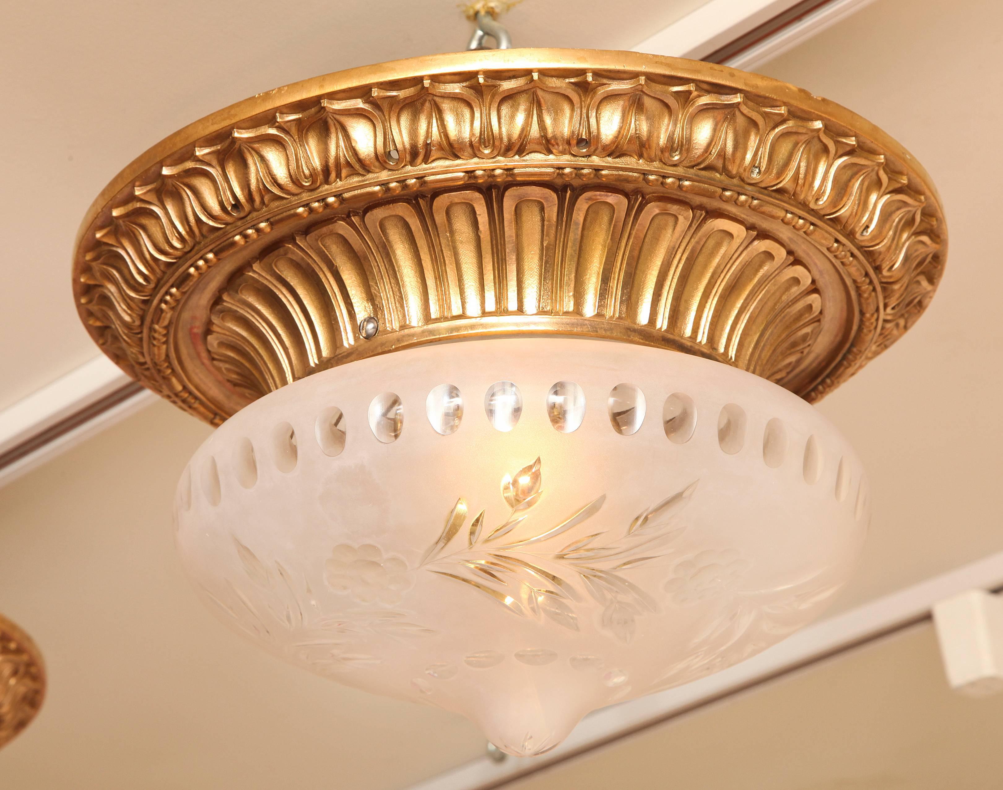 American bronze flush mounted fixture by maker Caldwell. The round frame with leaf tip border surrounding arch fluted inner rim securing dome shaped cut-glass shade. Floral, frosted glass domed shade with drop in center, concealing two Edison