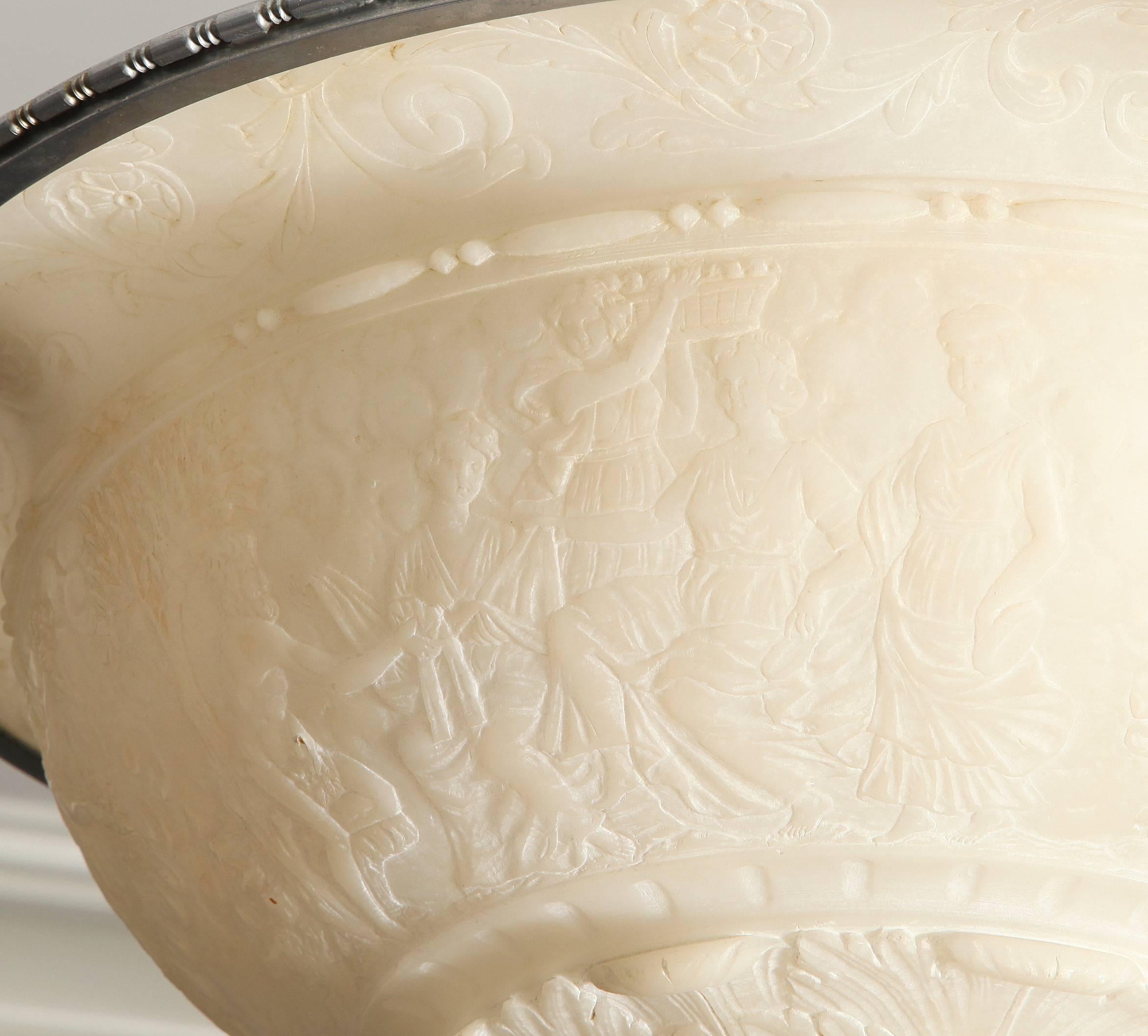 A neo-Classic design, cream colored alabaster pendant fixture, the alabaster without grey or black veining, hand-carved with classical design on the underside of the bowl, which is encircles by leaf-tip molded edge in nickel-plated bronze and