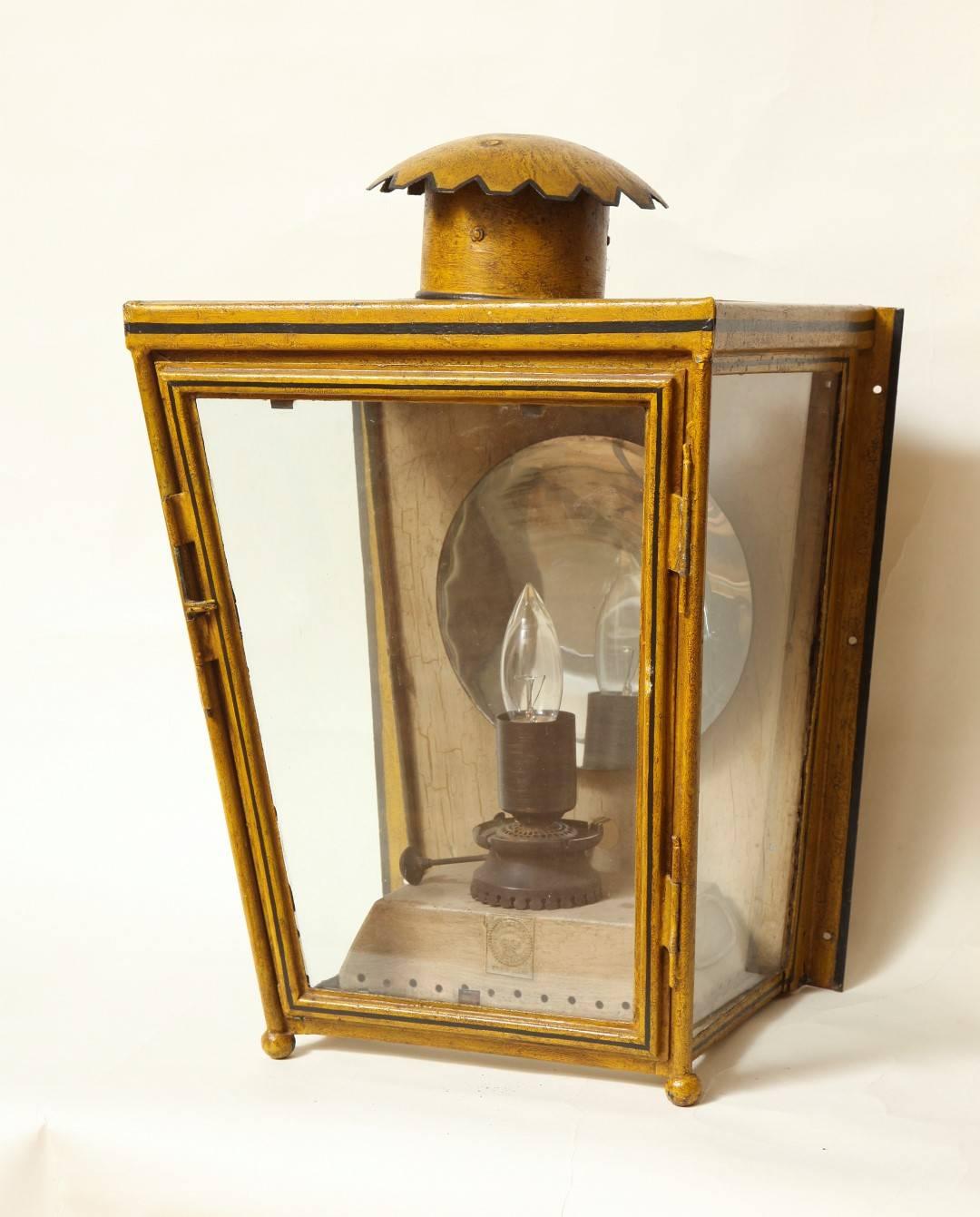 A French tole wall mounted lantern with glazed sides hinged door, the interior fitted with original oil burner now electrified and having concave mirrored reflector. Circa 1870.