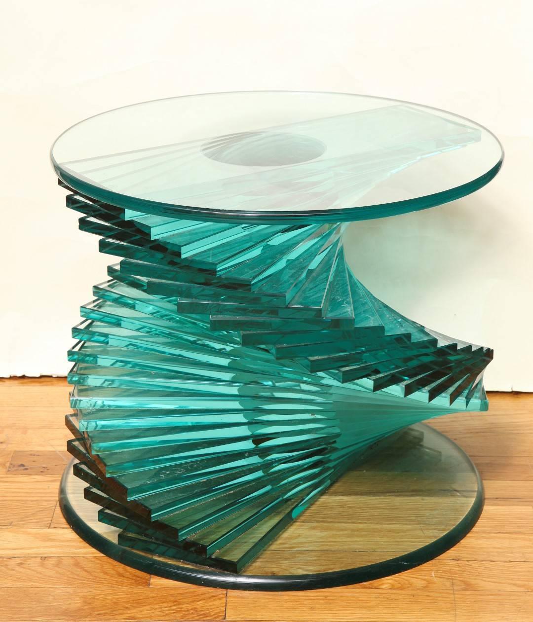 A side table designed with stacked sections of class spiraling from round base to round top with polished edge. 