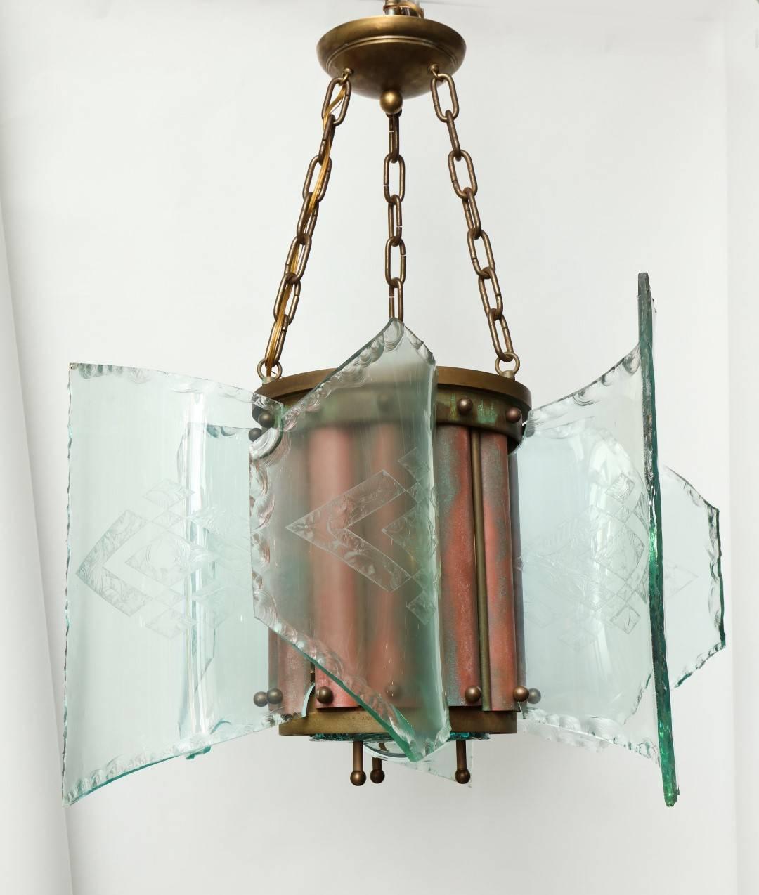 A Curved Glass American Arts & Crafts Style Ceiling Fixture. The cylindrical bronze frame suspended from four lengths of chain and having an enameled and patinated finish to the fixture body. The frame securing six curved rectangular sections of