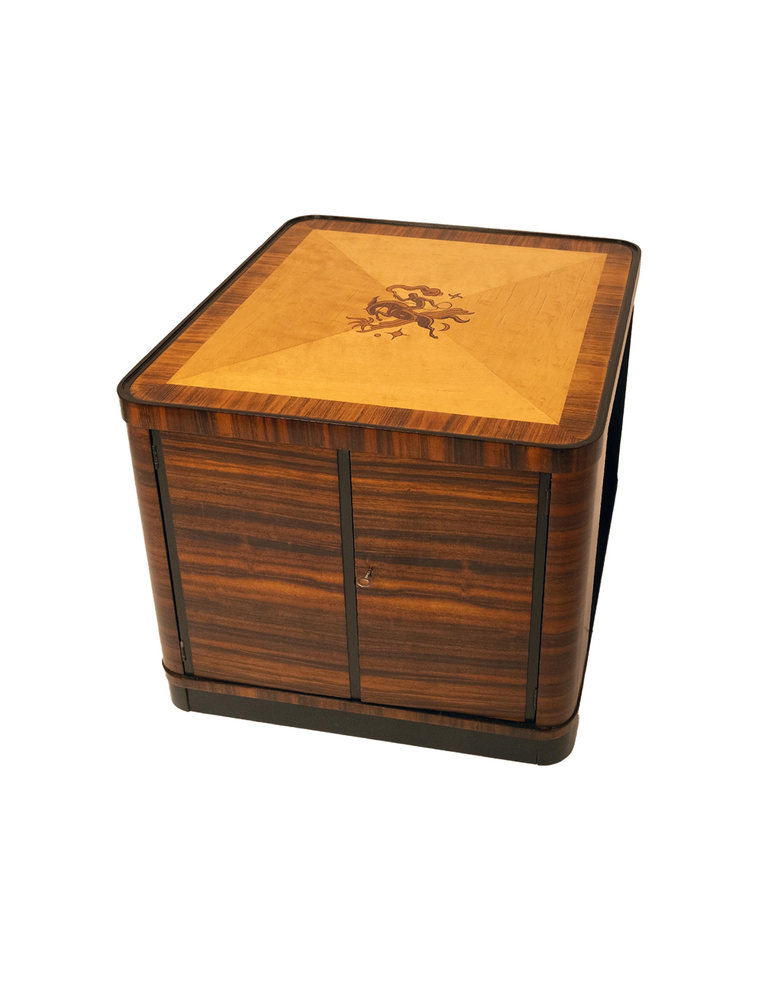 An Art Deco side table with a bar cabinet on one side. The top with a stylized marquetry design of a man on a horse. Circa 1930.