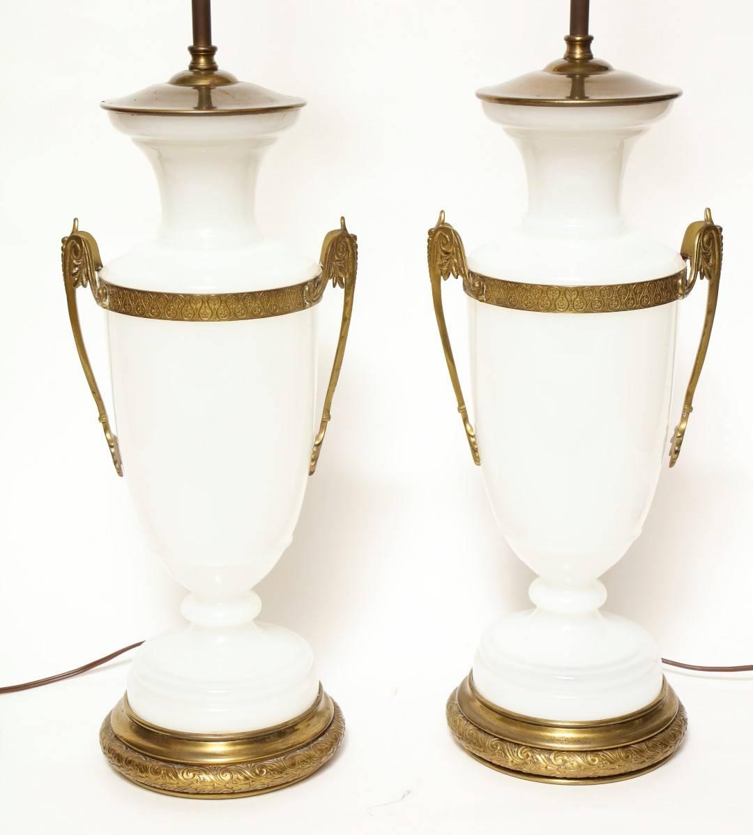 A pair of Charles X style opaline glass vases mounted as lamps, the baluster form body flanked by scroll handles, on a stepped base with etched Greek key motif, surmounted by pinecone finial.