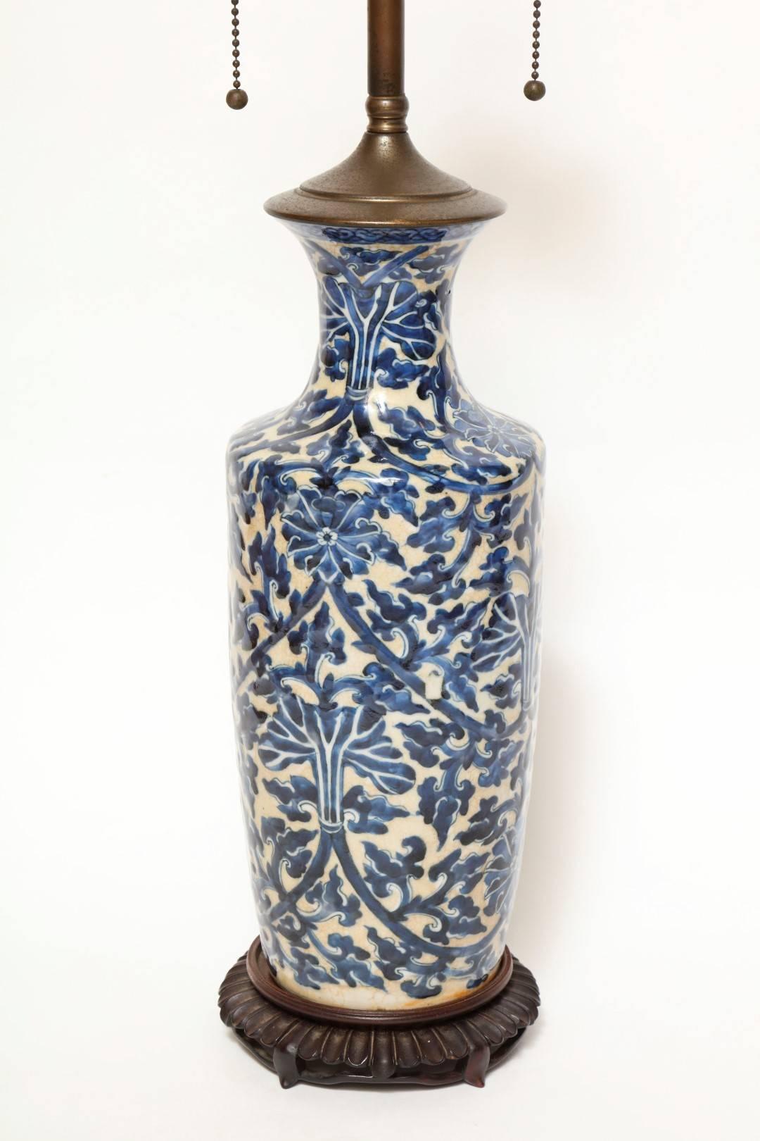 A blue and white Moorish style table lamp, in a blue and white trefoil motif, on circular gadrooned base with four feet, the double cluster fitting surmounted by a turned stem with finial.