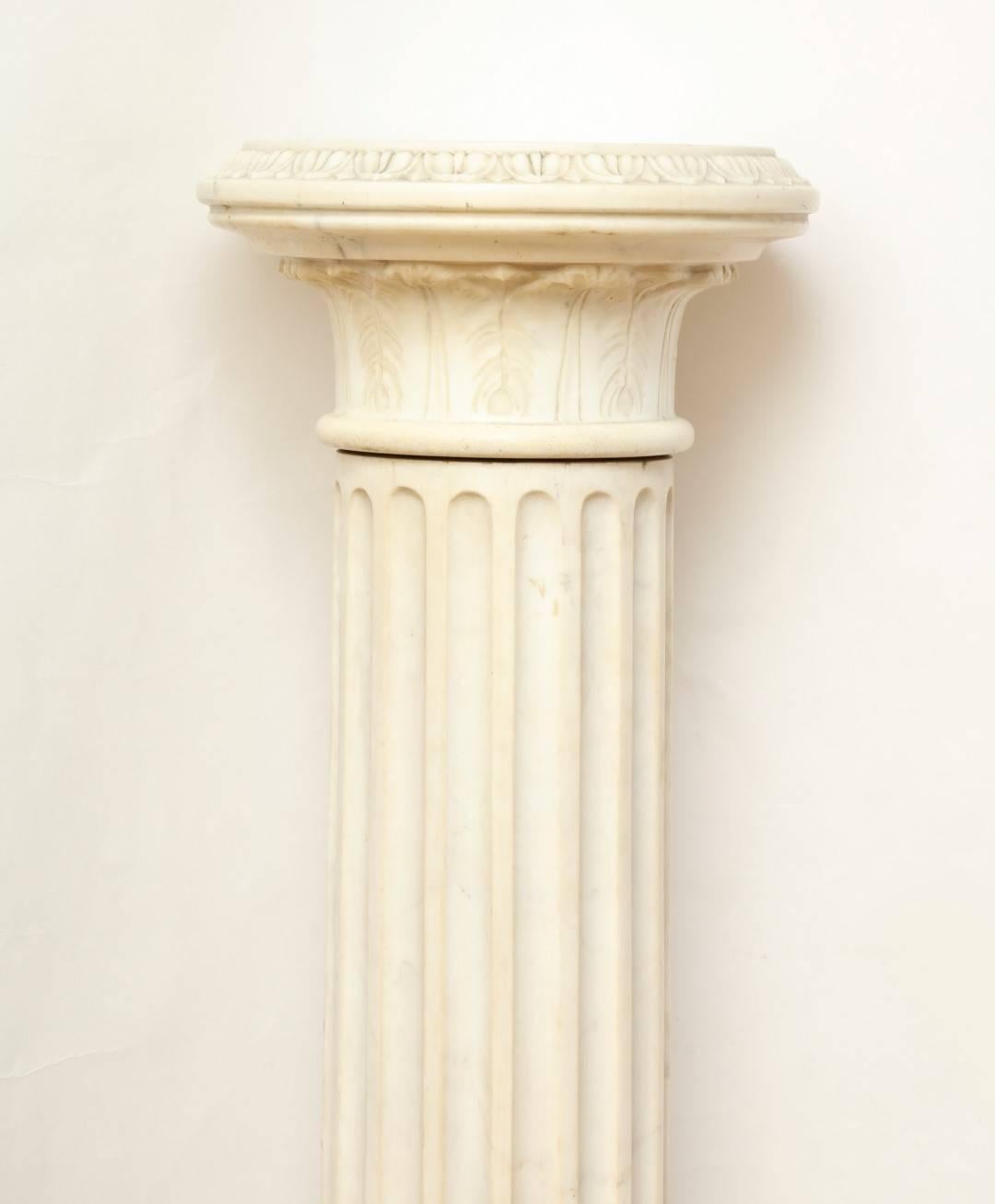 A marble Corinthian capital architectural pedestal, the fluted shaft with an egg and dart wasted socle on a square base, the removable top carved as a Corinthian capital with everted egg and dart rim.
 