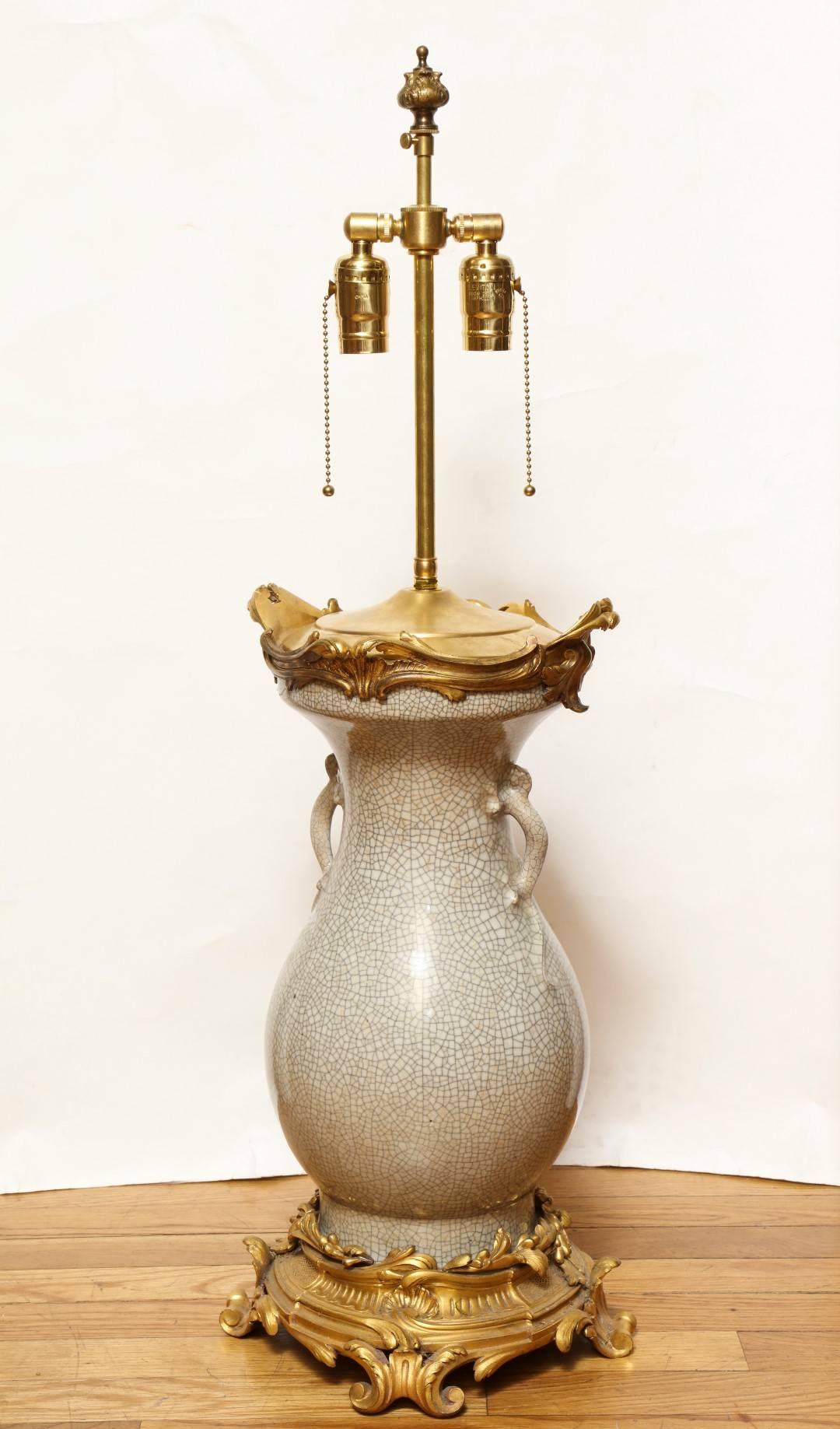 A Louis XV style ormolu-mounted crackle glaze porcelain vase, the baluster shaped body with pierced ring handles, the neck mounted with pierced acanthus, on scrolling rocaille plinth.
 
31.5