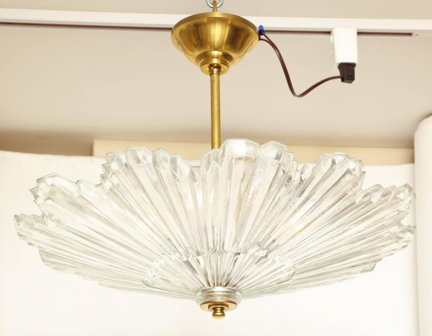 A Caldwell scalloped edged glass sunburst ceiling light with ridged vertical lines suggesting sunrays, the glass interior to diffuse three candelabrum sockets (Two Available).