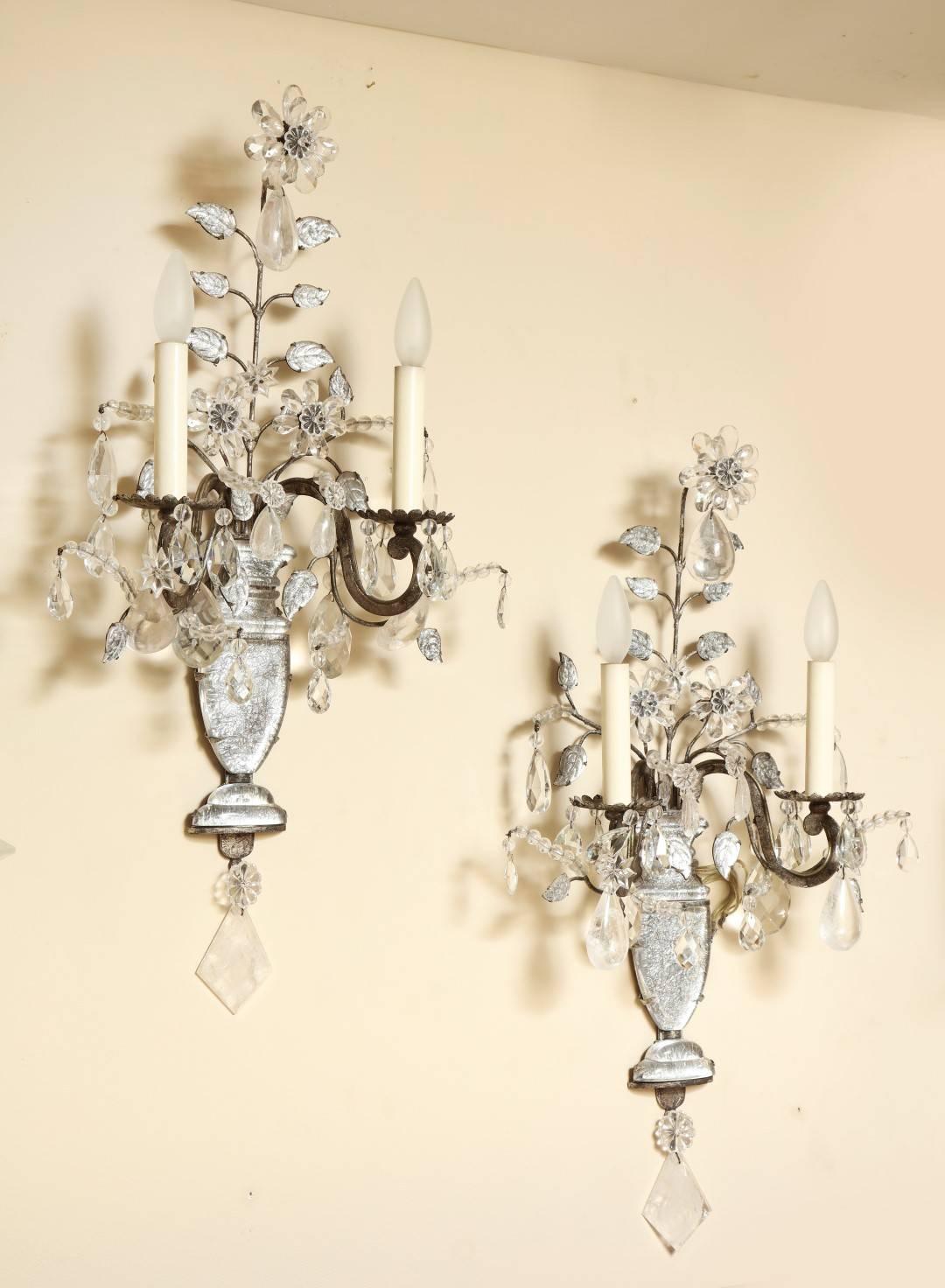 A pair of French Maison Bagues two-light wall sconces with silver gilt iron frames mounted with molded glass vase shaped elements backed with silver leaf. Each backplate issuing branches with individual crystal leaves and flowers formed of crystal