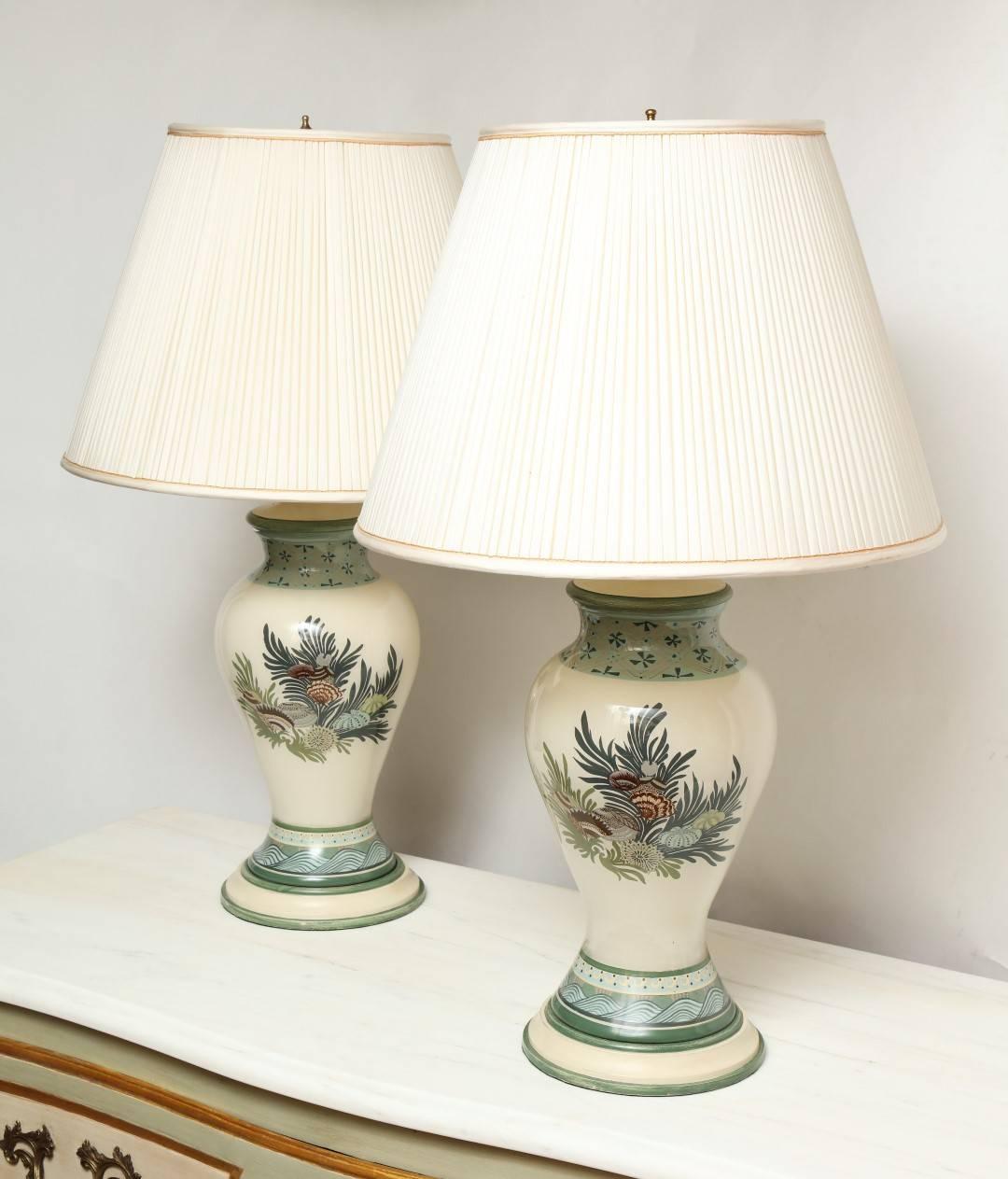 A pair of reverse glass painted lamps, the baluster shaped body depicting a foliage motif in complementary shades of green, with custom-made base and custom-made lamp shades included.

30