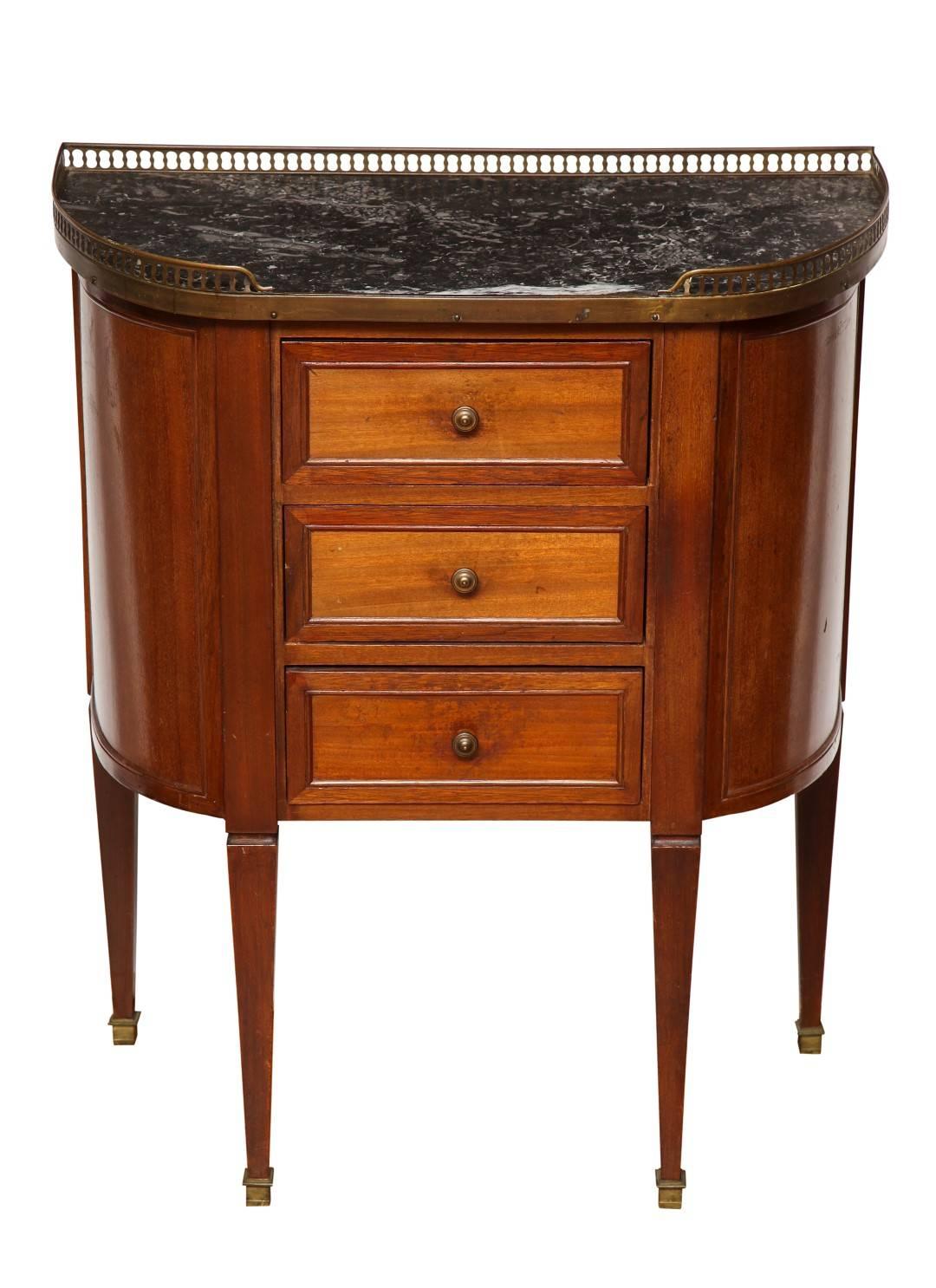 A pair of fruitwood bombe-form bedside tables, on Sheraton legs, the front with three drawers each with a circular metal pull. The top with a pierced metal gallery, surrounding a grey stone top.