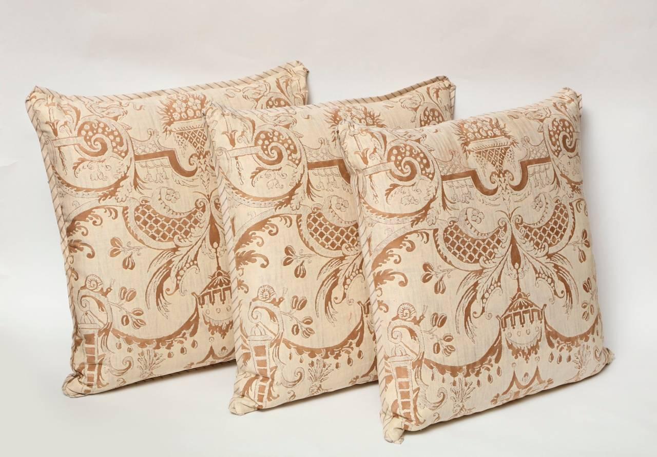 A set of three Fortuny fabric cushions in the Mazzarino pattern, tan and brown color way with striped silk bias edging and matching backs, the pattern, a 17th century French design named after Cardinal Mazarin at the court of Louis XIII and Louis