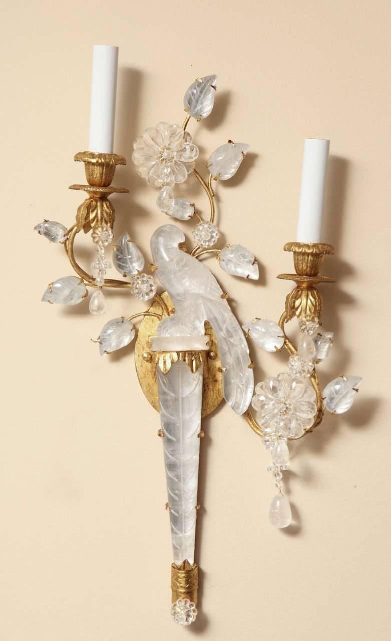 A pair of symmetrical right and left facing two-light gilt metal sconces in the manner of Bagues with the firm's signature bird carved in rock crystal surrounded by sprays of branches and leaves.