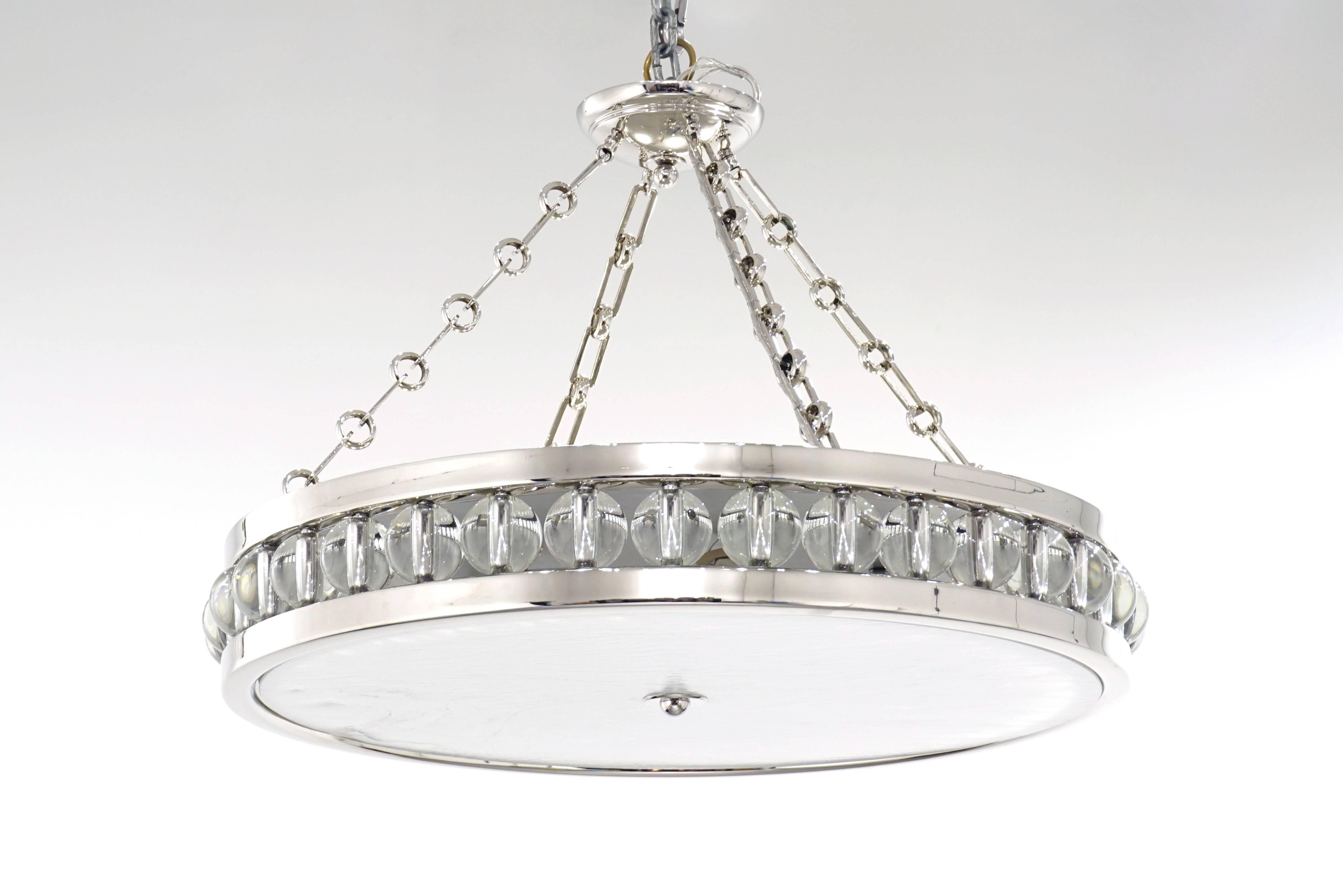 A large, polished nickel pendant light fixture suspended from chain and canopy. The Tambour Pendant Light features a 30