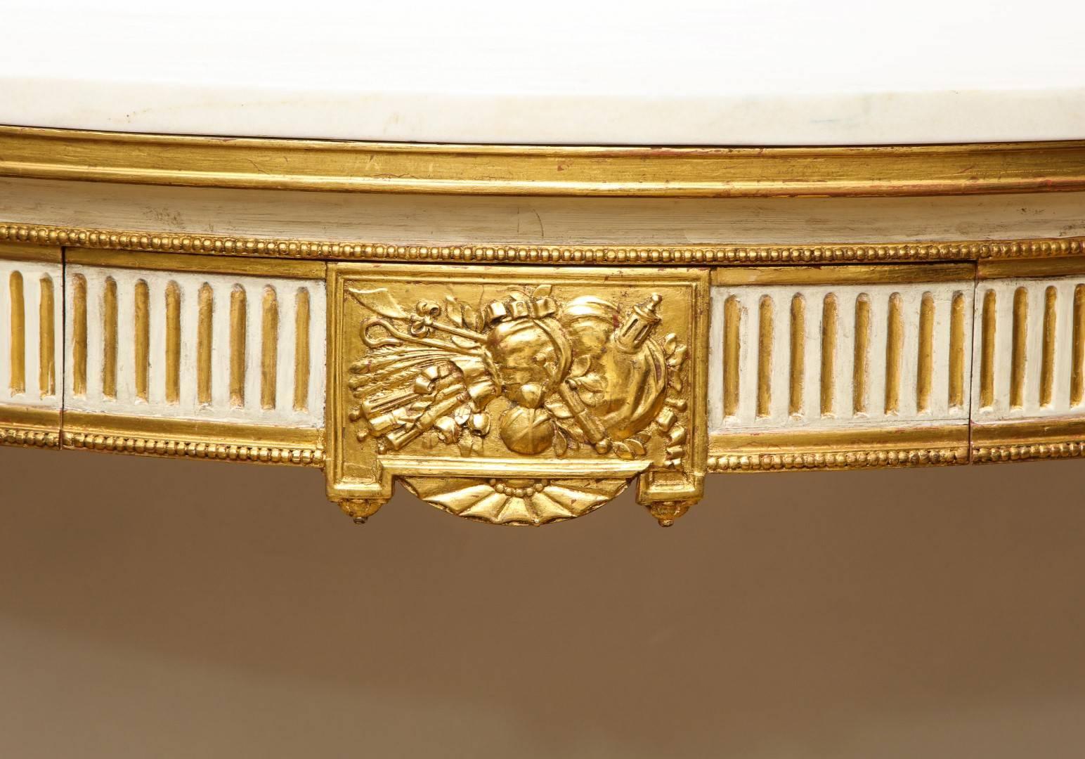 A French Louis XVI style demilune console, with a drawer in the apron, having gilt fluting and beaded edge. The centre of the shaped apron with rectangular trophy medallion below gilt molded edge and Rosa Aurora marble tops. The four round tapering